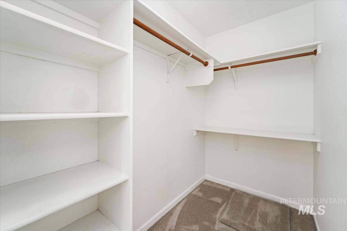 Walk in closet with dark colored carpet