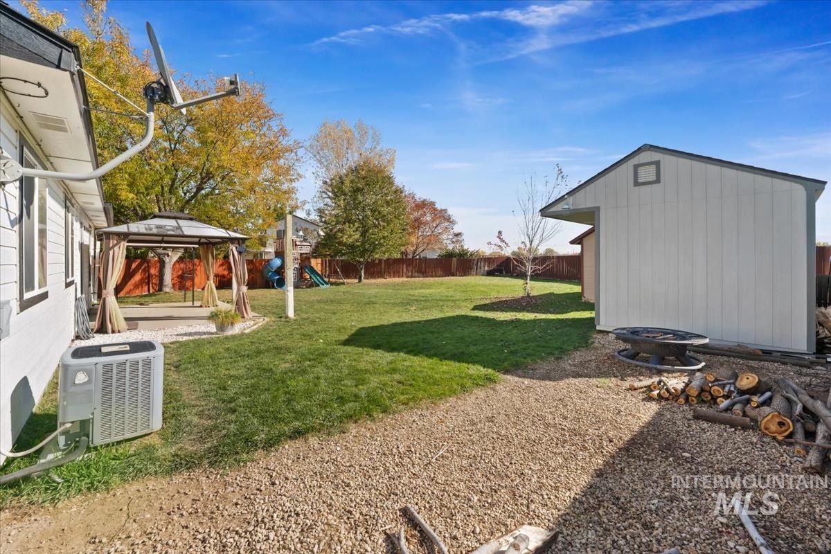 Fenced backyard with a gazebo, an outdoor fire pit, a playground, a shed, and a patio