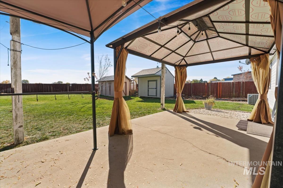Fenced backyard featuring a gazebo, a storage shed, and a patio area