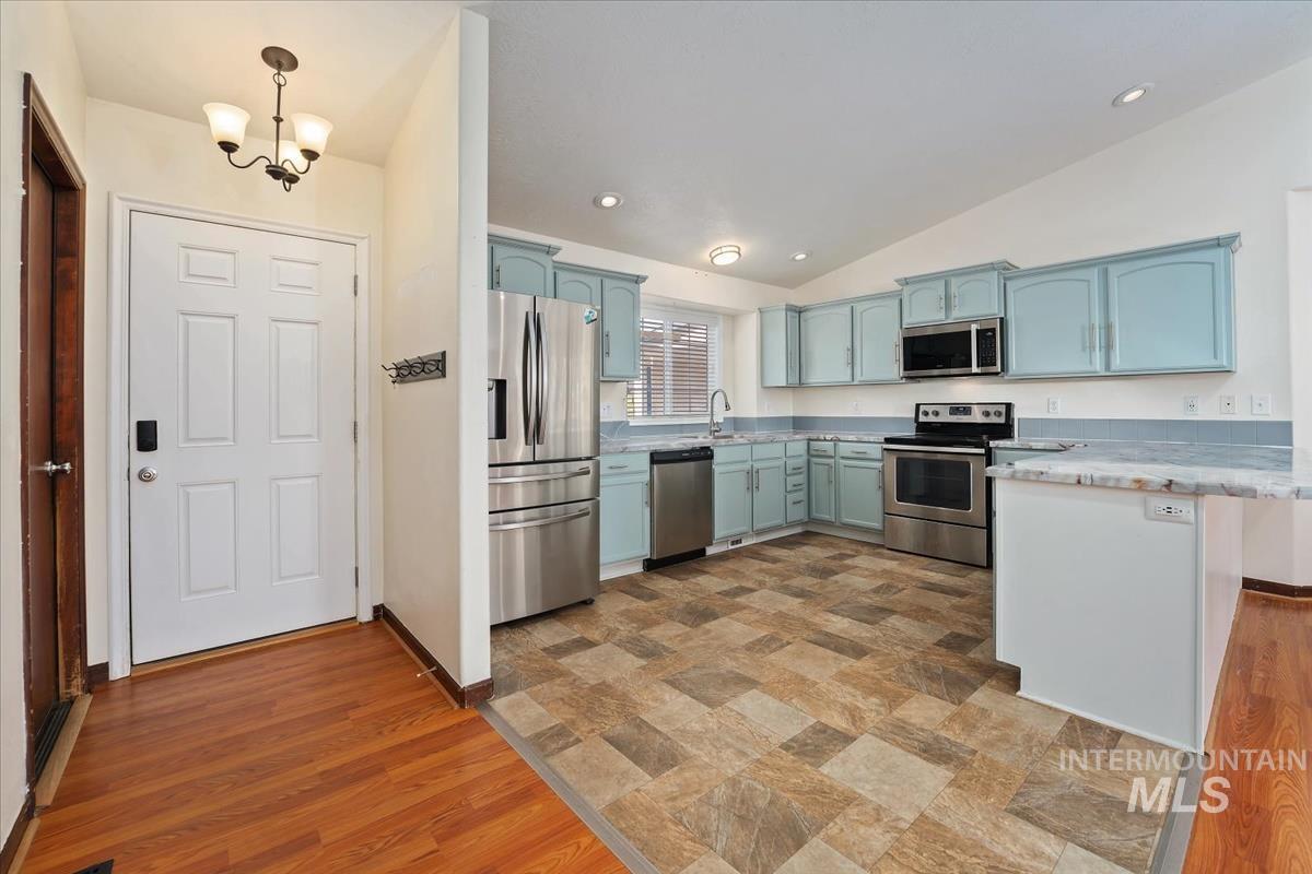 Kitchen with appliances with stainless steel finishes, lofted ceiling, a peninsula, light wood finished floors, and recessed lighting