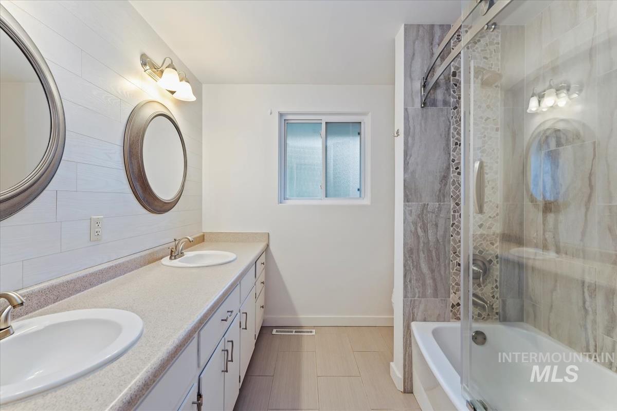 Bathroom with double vanity and tiled shower / bath combo