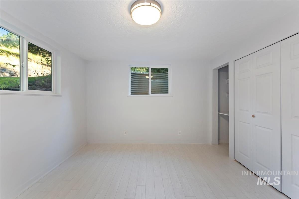 Unfurnished bedroom featuring light wood-type flooring, a closet, and a textured ceiling