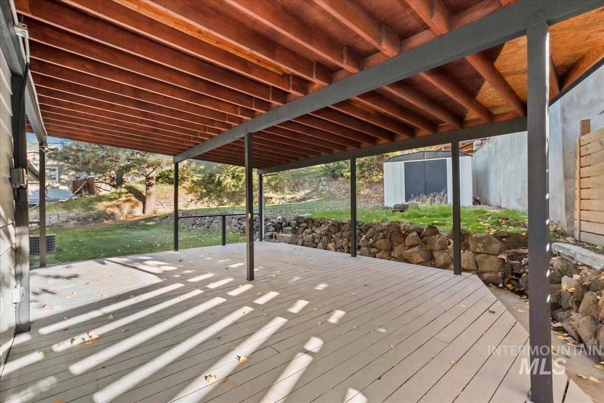 Wooden terrace with a storage shed and a lawn