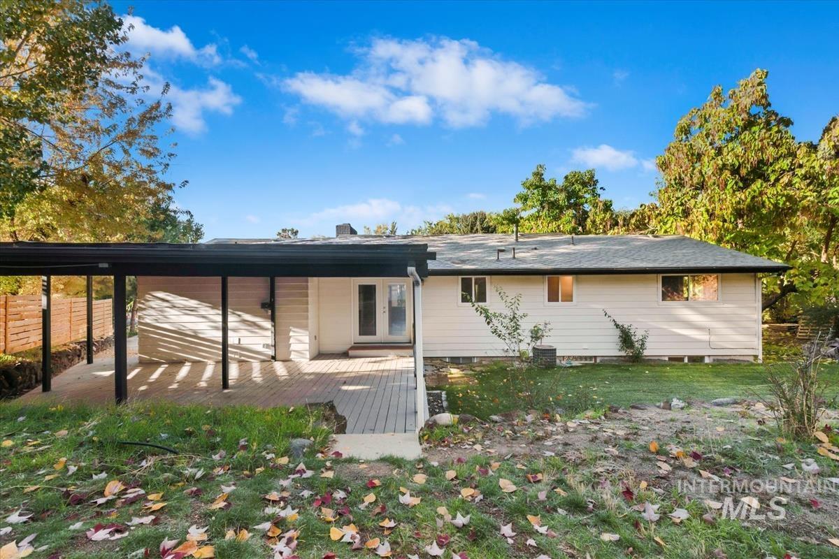 Rear view of house featuring a wooden deck, a chimney, and a lawn