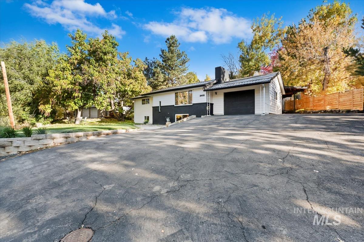 View of front of property with a metal roof, a chimney, and asphalt driveway