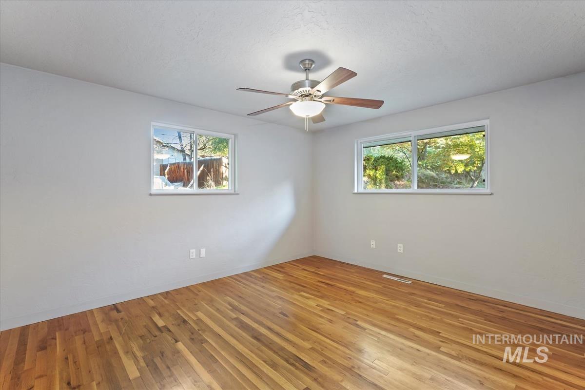 Empty room with light wood-style floors and a ceiling fan