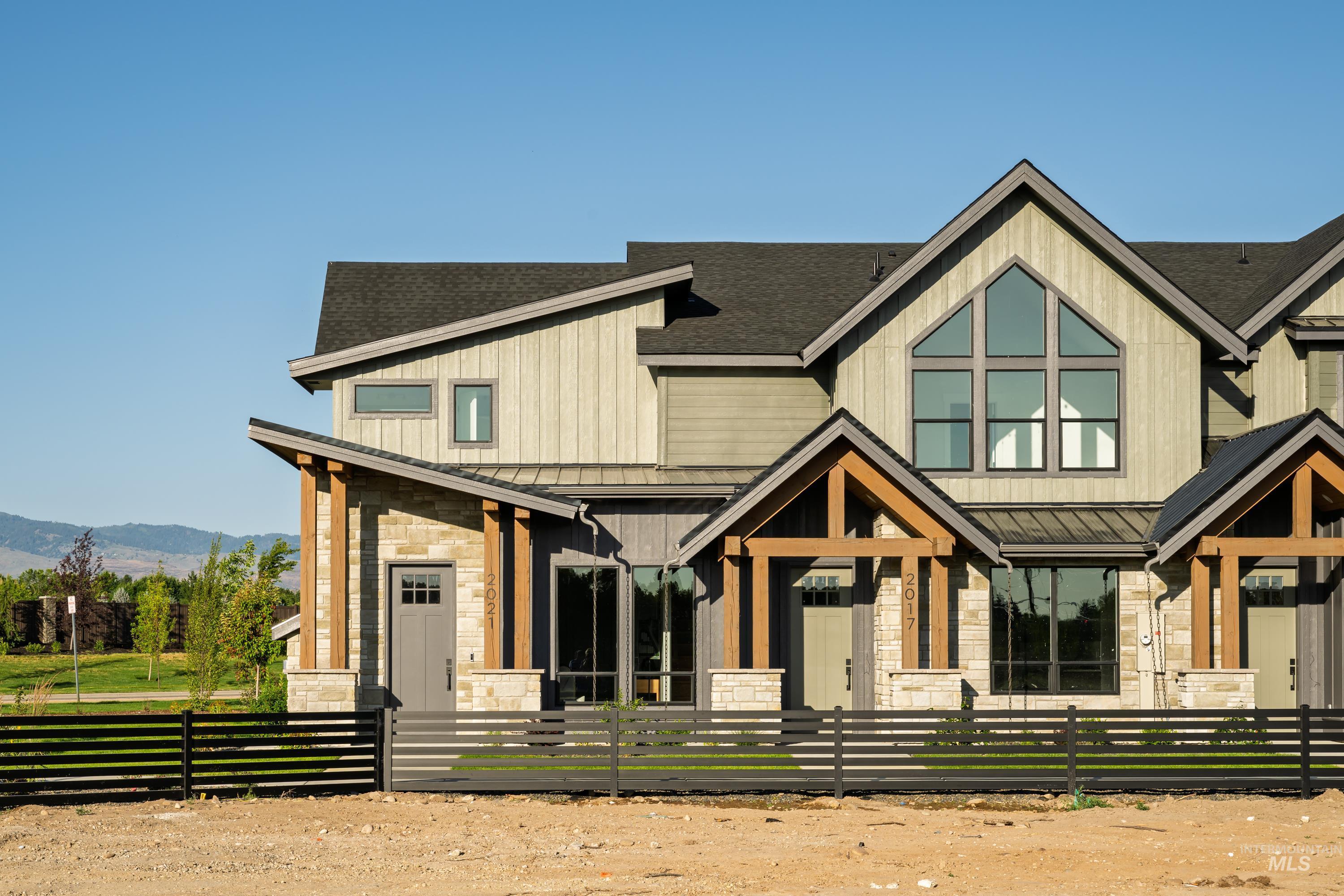 View of front of home with a standing seam roof, stone siding, a mountain view, a shingled roof, and a metal roof