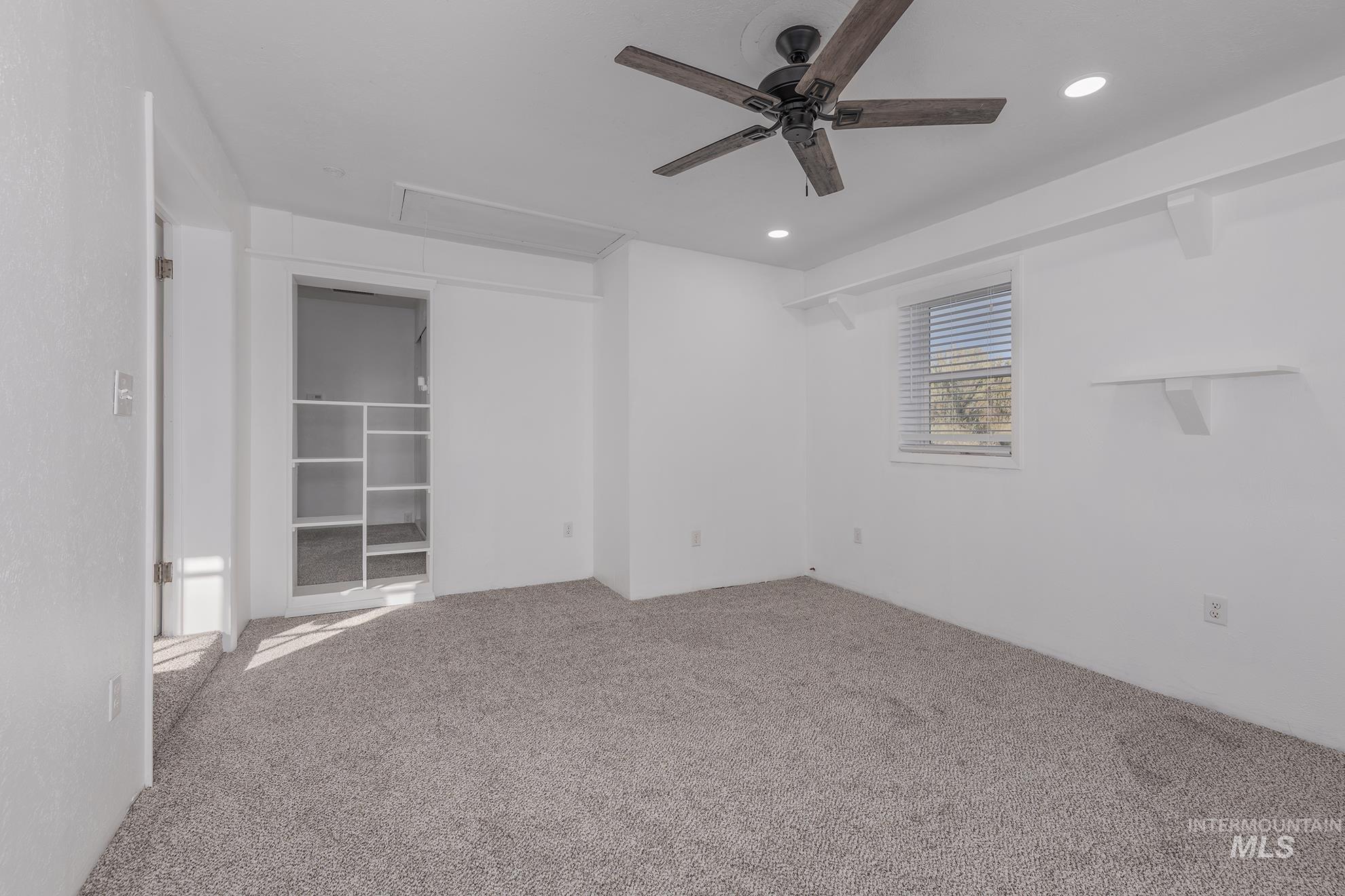 Empty room with carpet floors, a ceiling fan, recessed lighting, and attic access