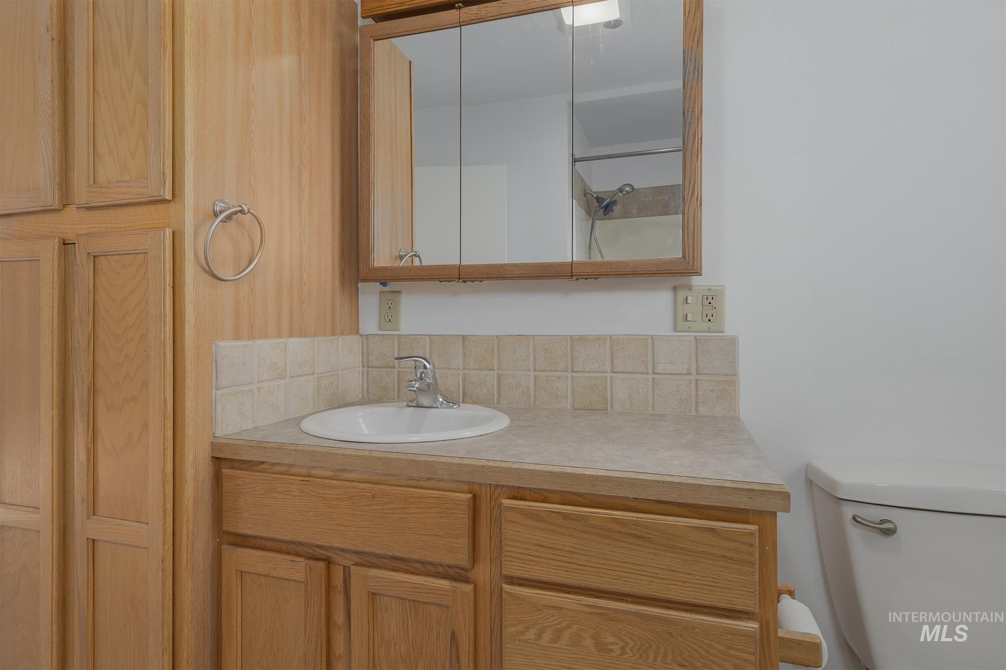 Bathroom with vanity, a shower with shower door, and decorative backsplash