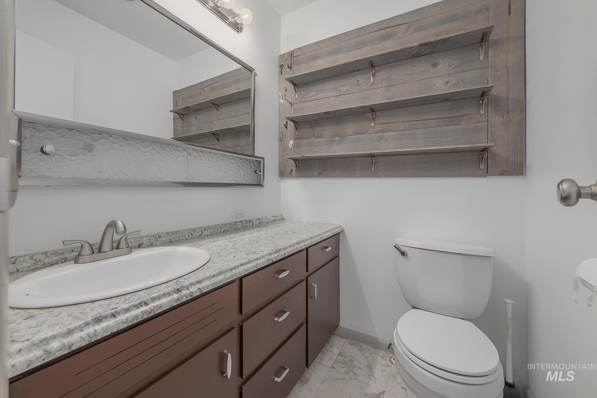 Half bathroom with vanity and light marble finish flooring