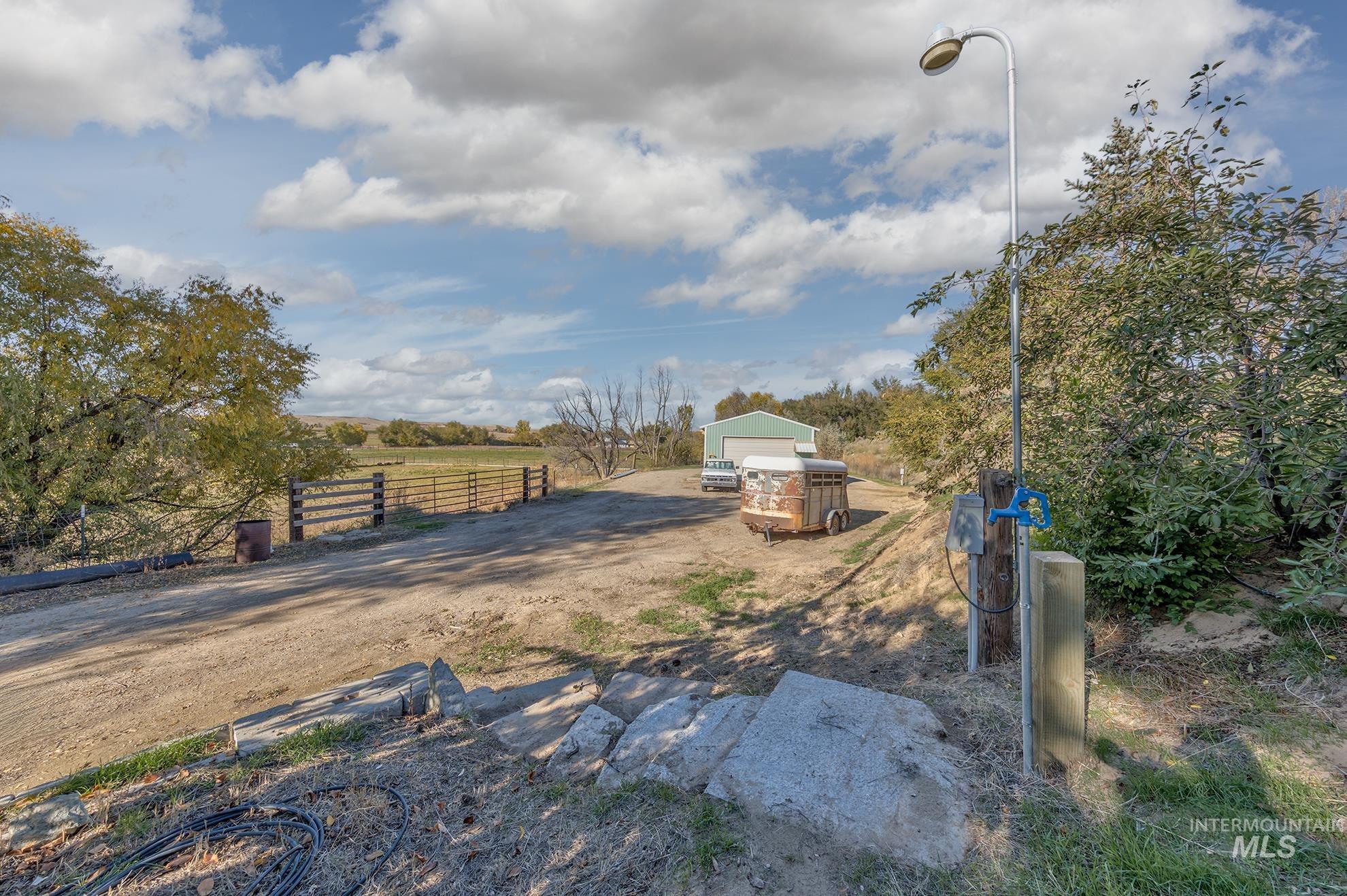 View of yard featuring an outdoor structure, a rural view, dirt driveway, and a garage