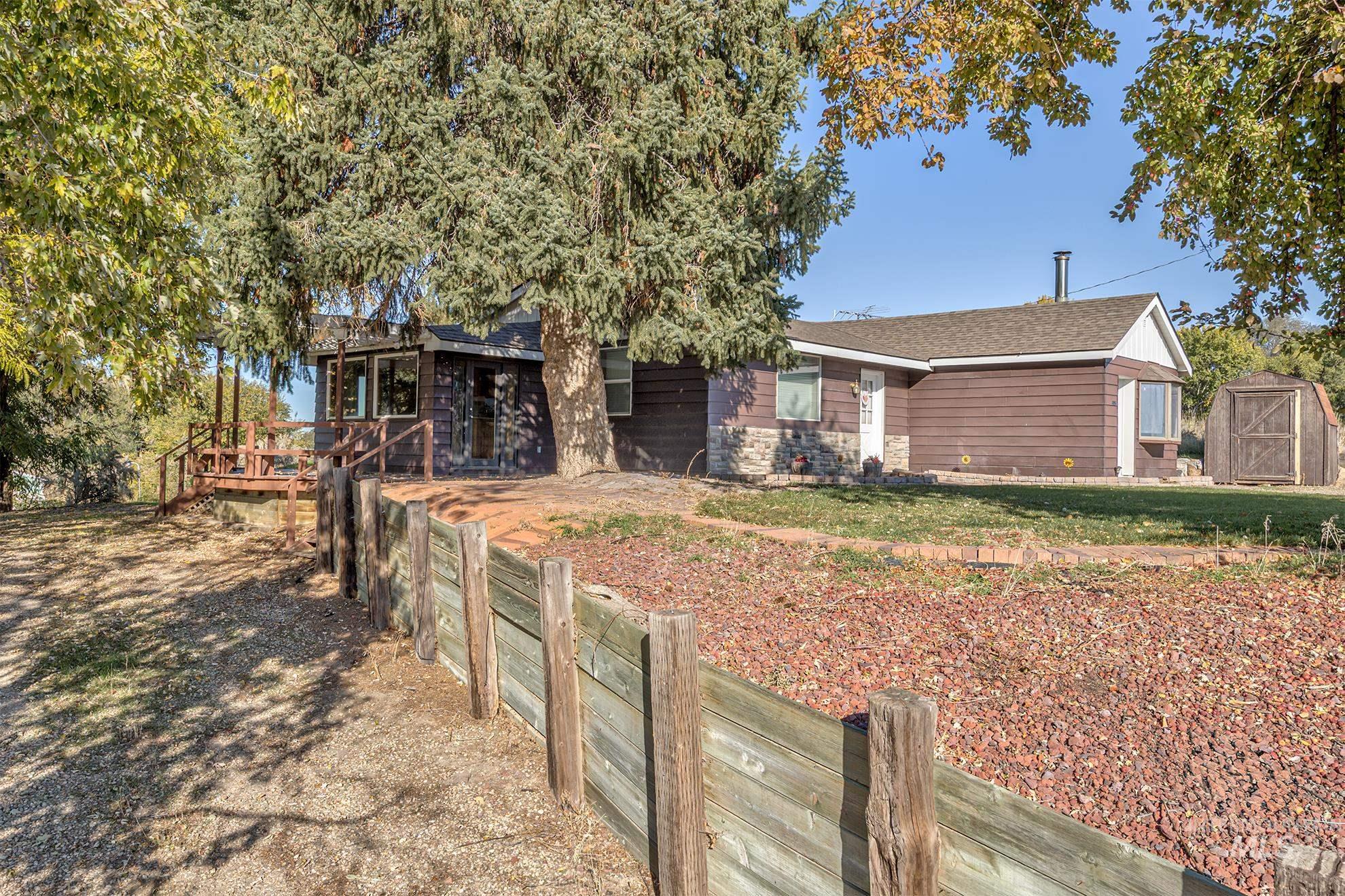 View of front of house with a wooden deck, a storage shed, and a shingled roof