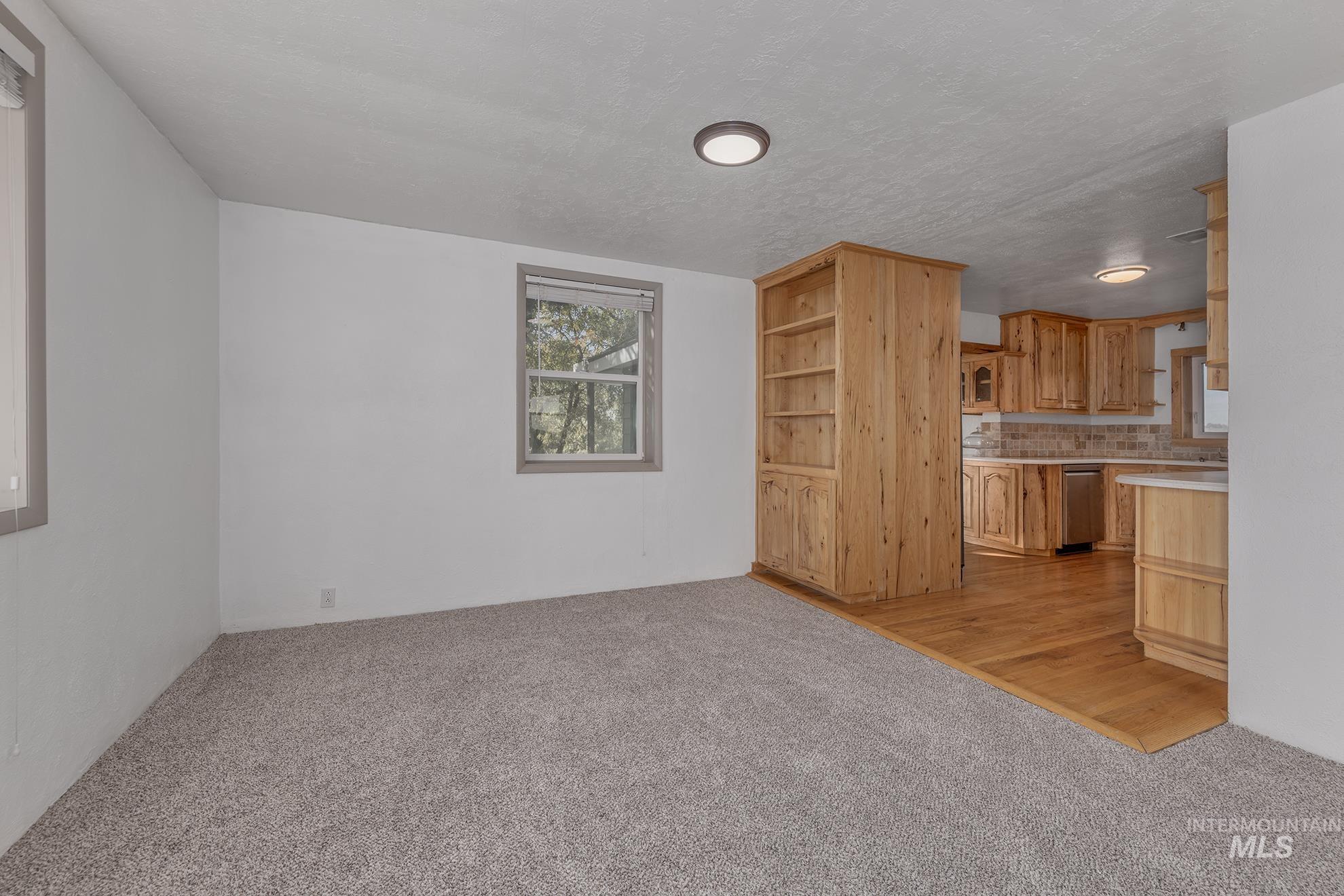 Kitchen with light countertops, tasteful backsplash, light carpet, light wood-style floors, and open shelves