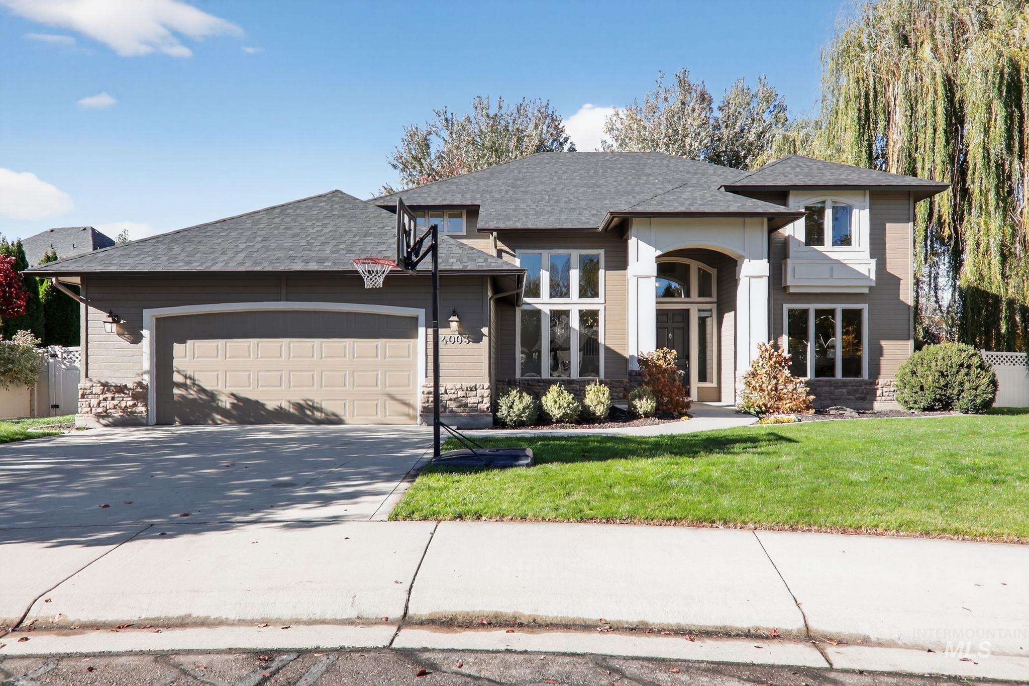 View of front of home featuring concrete driveway, a garage, a shingled roof, and stone siding