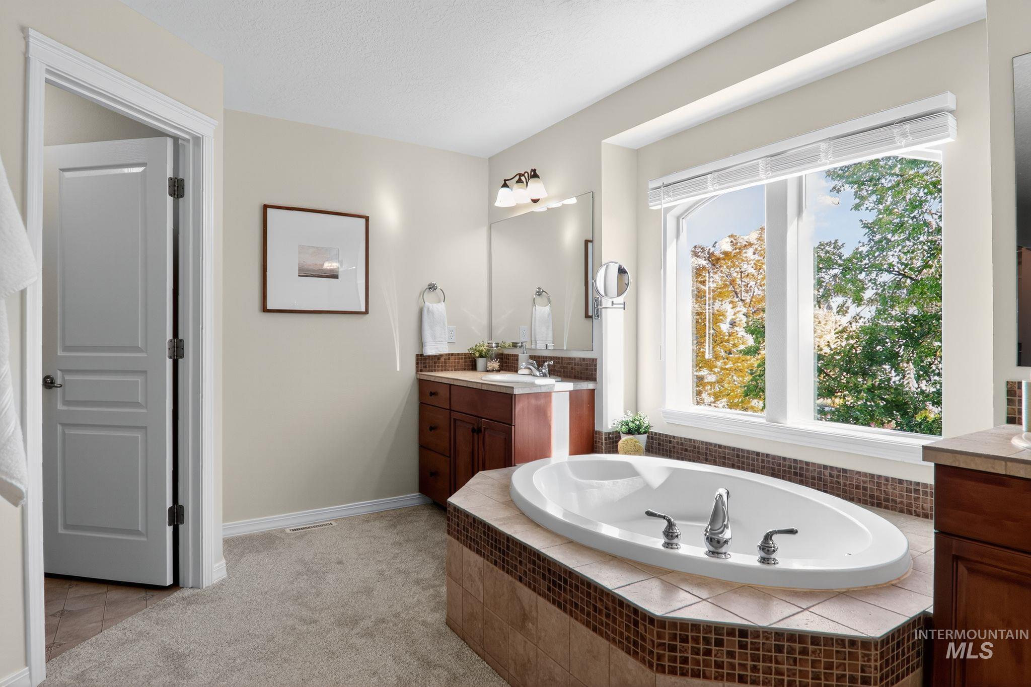 Full bathroom featuring a bath, vanity, and light colored carpet