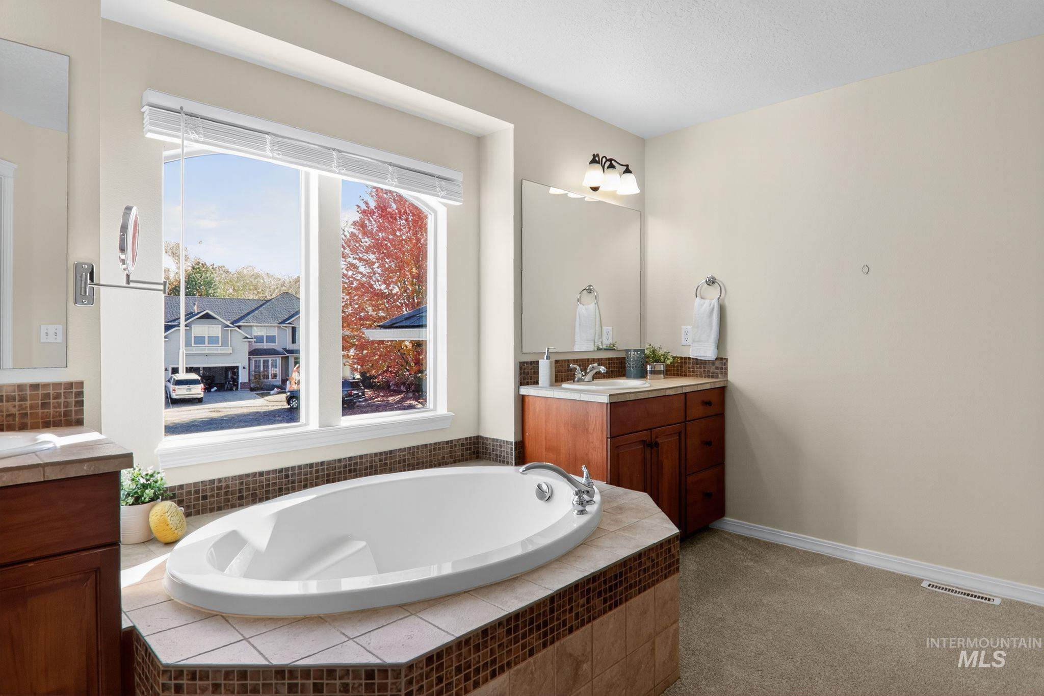 Bathroom with vanity, a bath, and light colored carpet