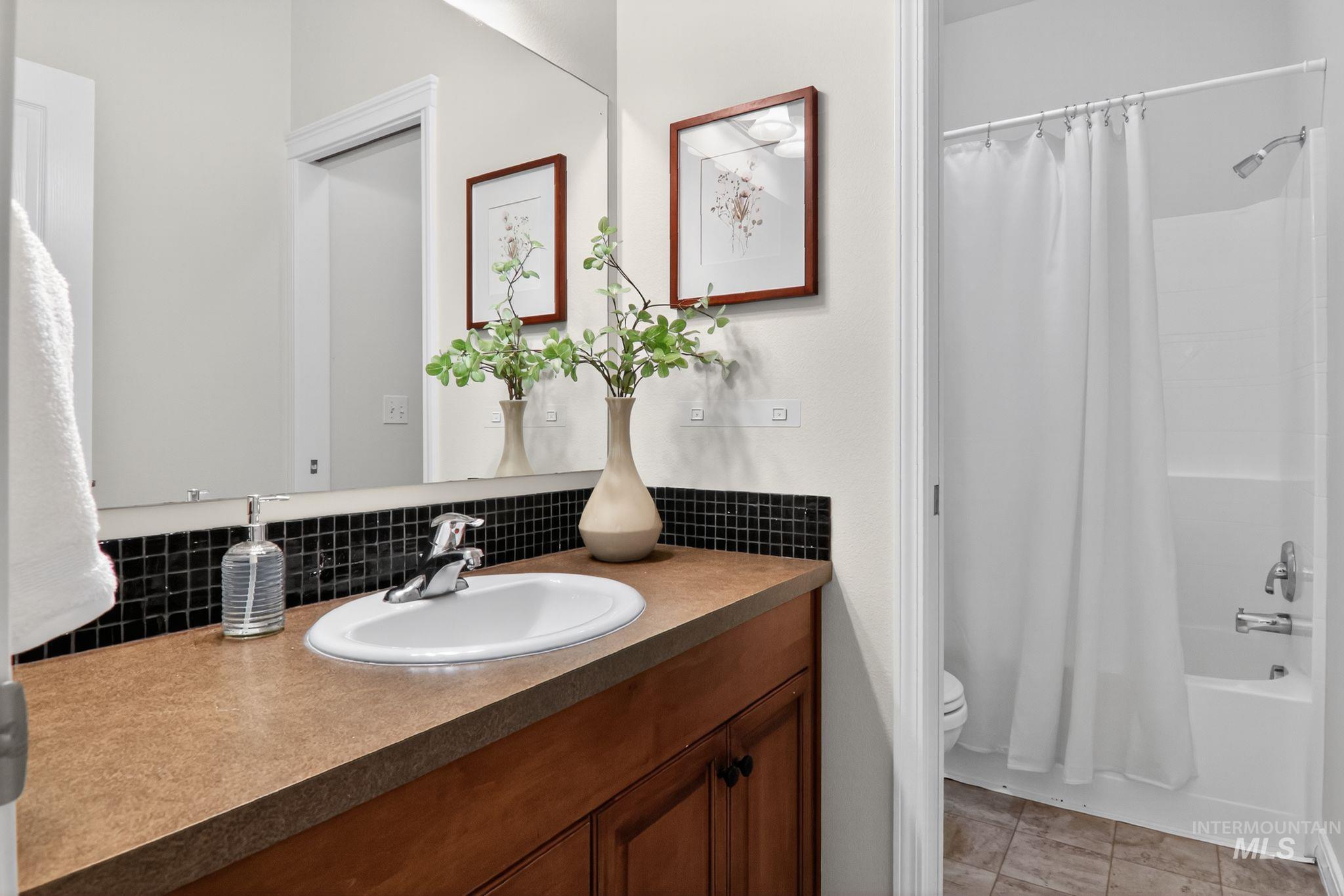 Bathroom with shower / bath combination with curtain, vanity, backsplash, and light tile patterned floors