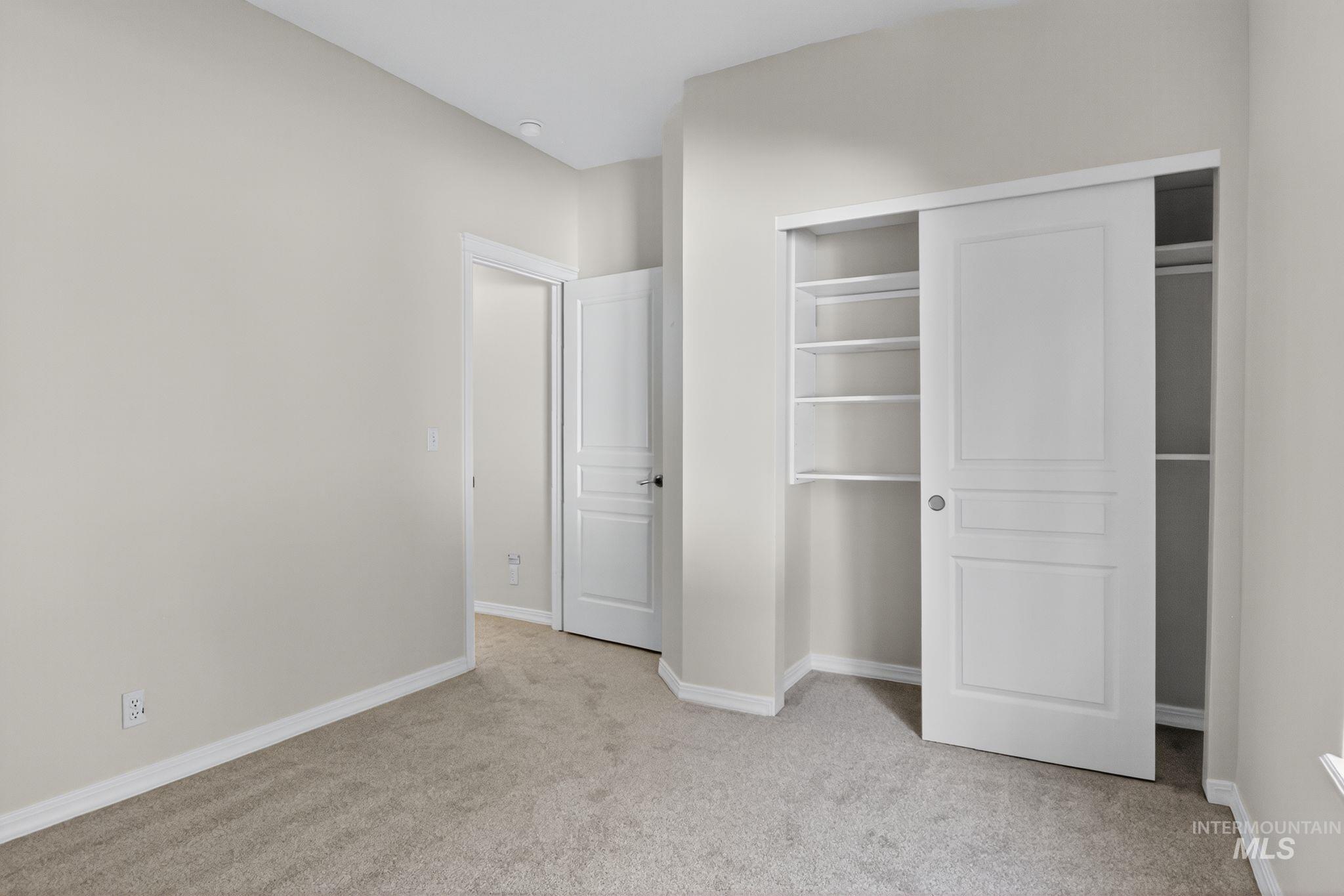 Unfurnished bedroom with light carpet and a closet