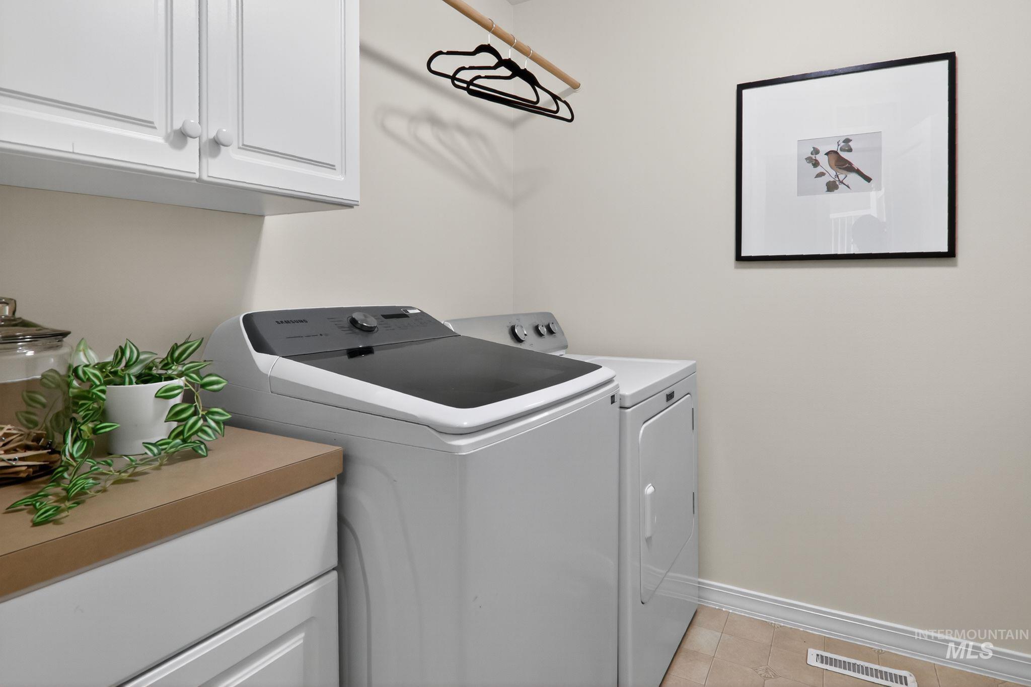 Laundry area featuring cabinet space, independent washer and dryer, and light tile patterned floors