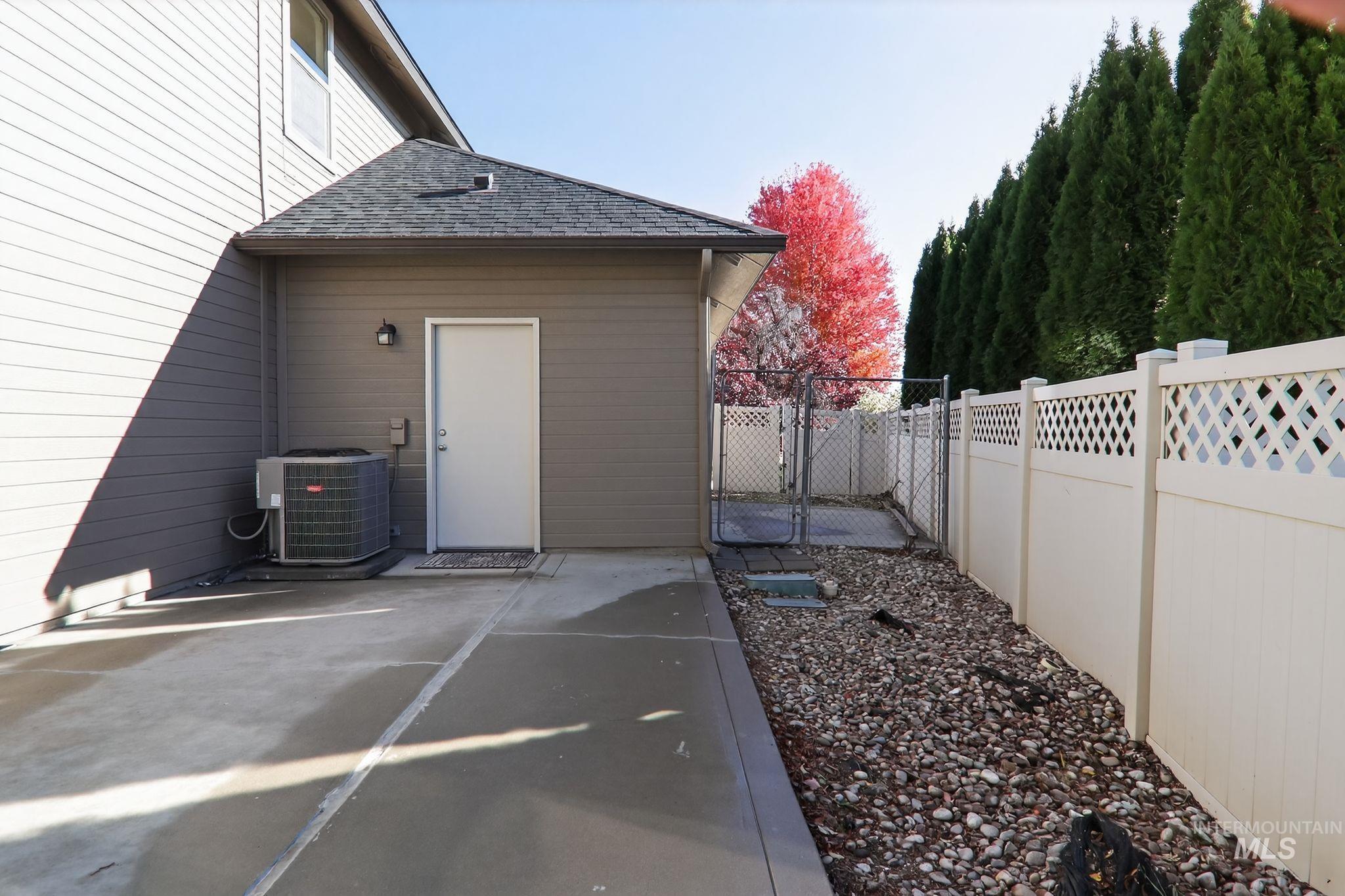 View of home's exterior with a fenced backyard, roof with shingles, a gate, and a patio area