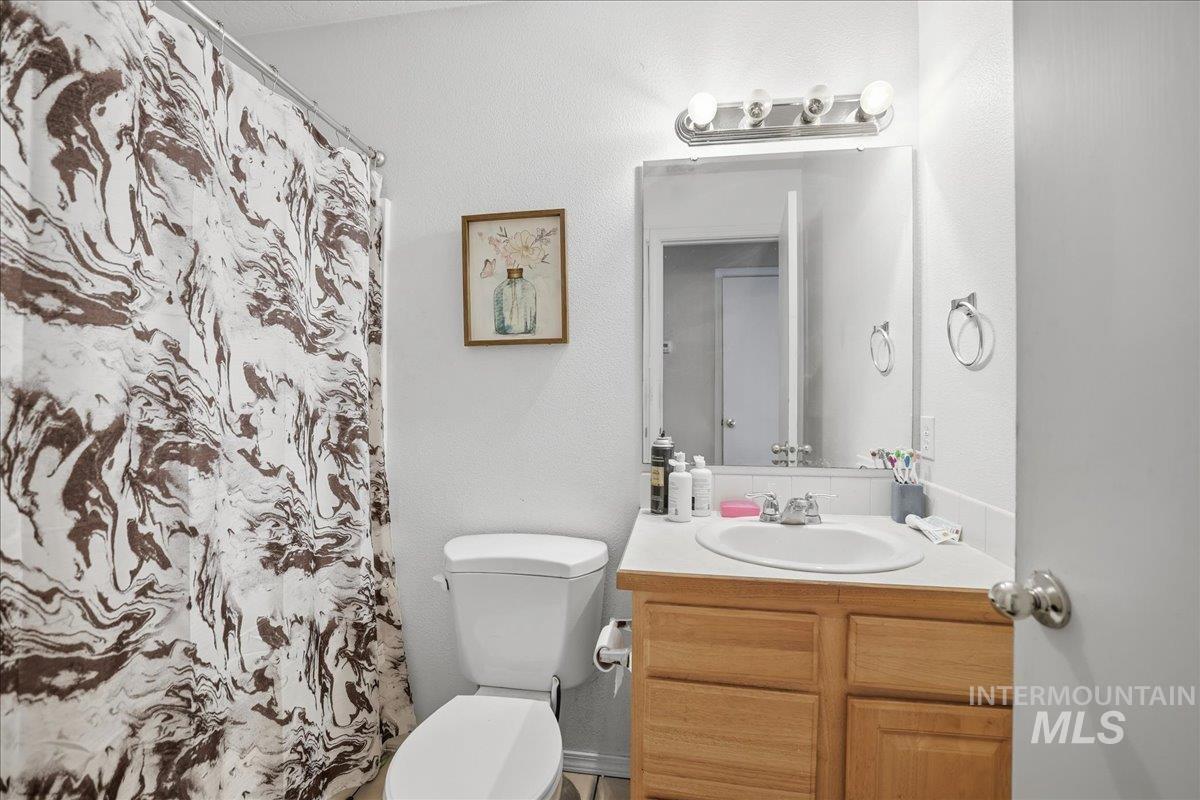 Full bath featuring vanity, curtained shower, and a textured wall