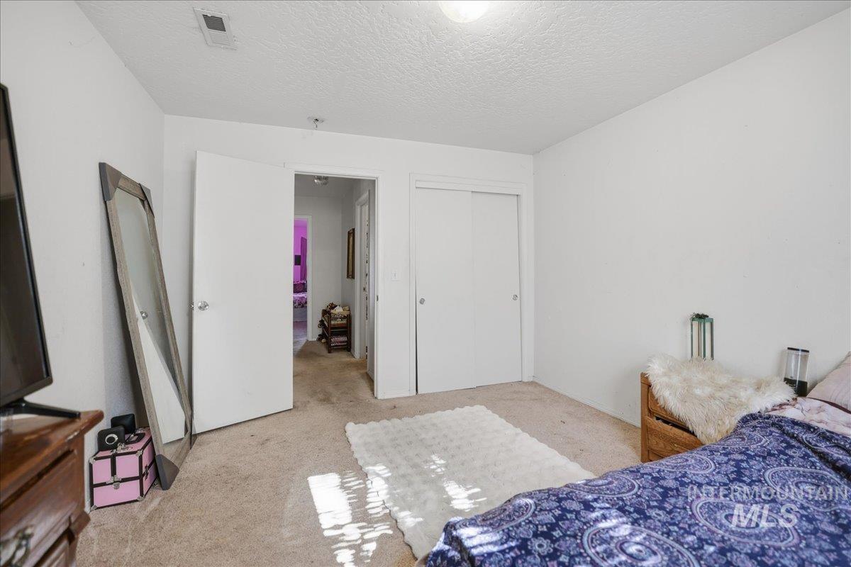 Bedroom with light carpet, a textured ceiling, and a closet