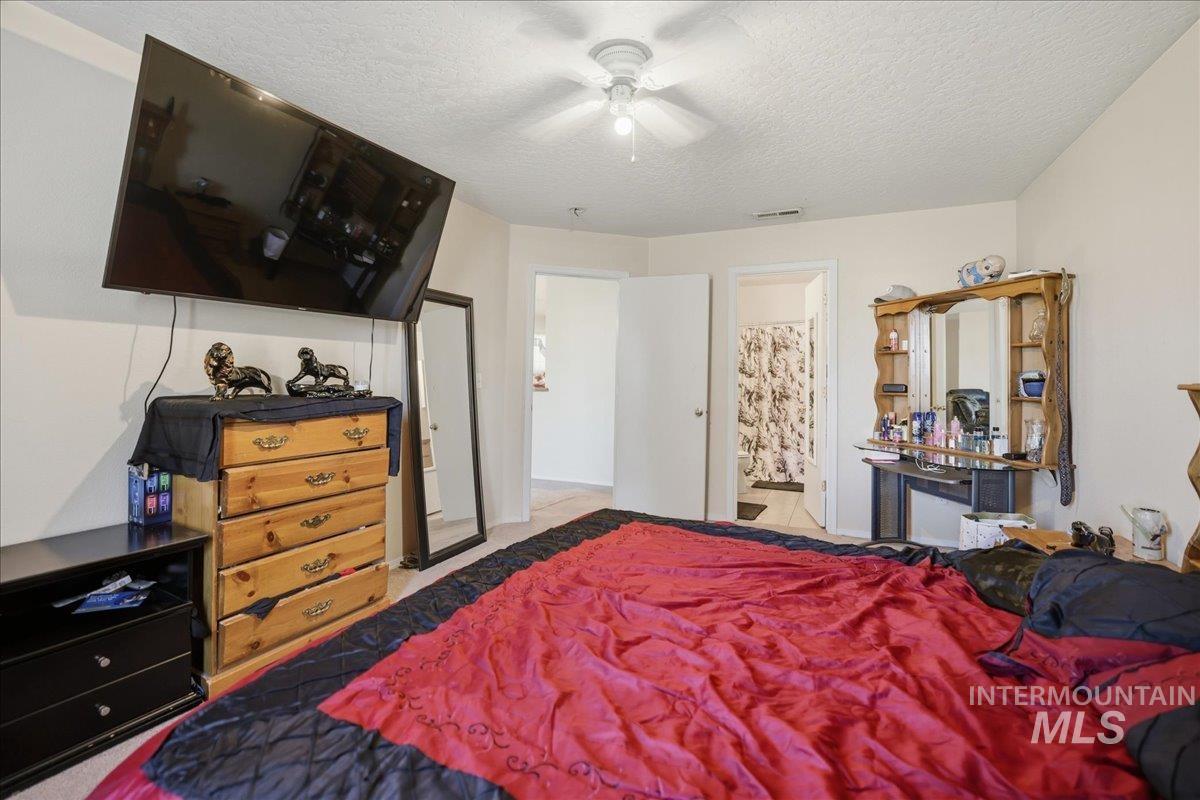 Bedroom featuring a textured ceiling, a ceiling fan, and ensuite bath