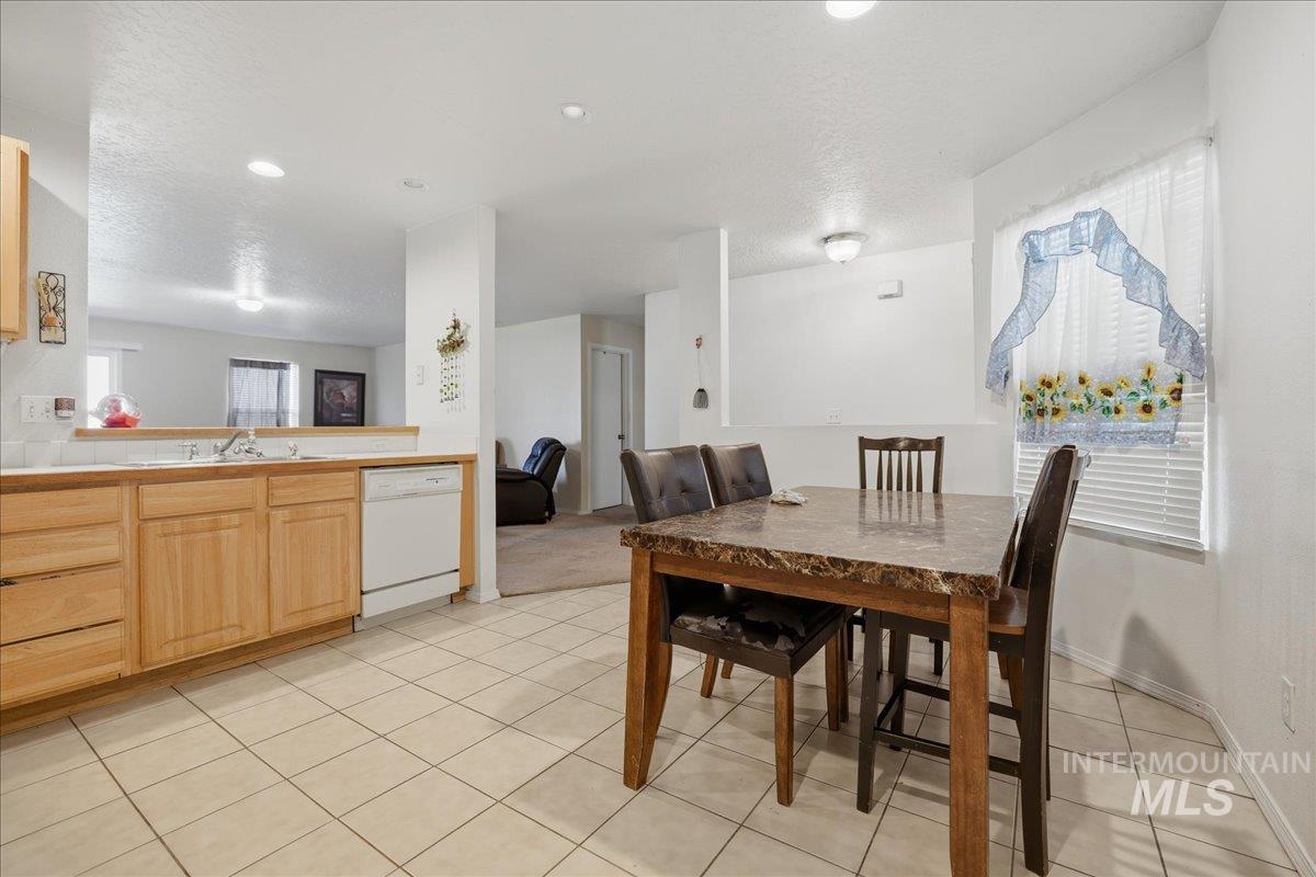 Dining area featuring light tile patterned floors, a textured ceiling, and recessed lighting