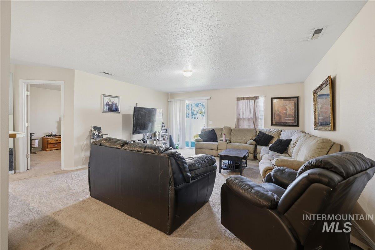 Carpeted living room featuring a textured ceiling and baseboards