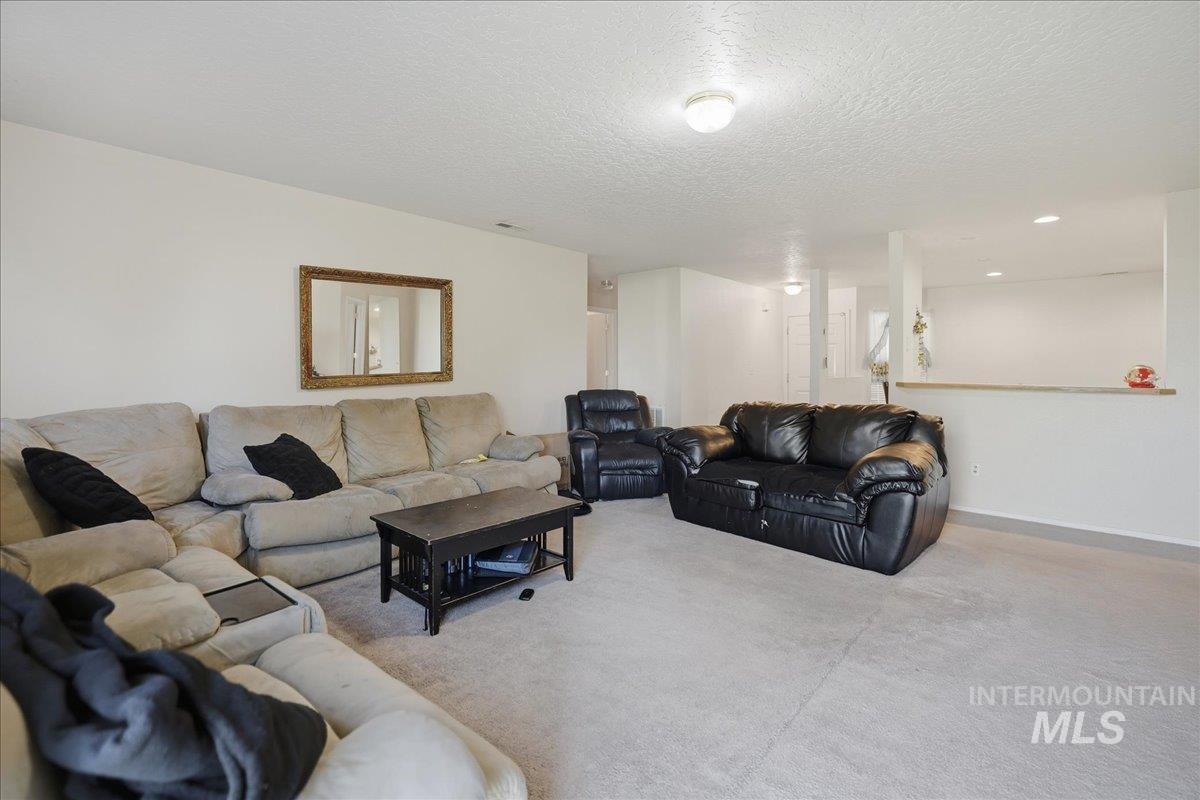 Carpeted living area featuring a textured ceiling and baseboards