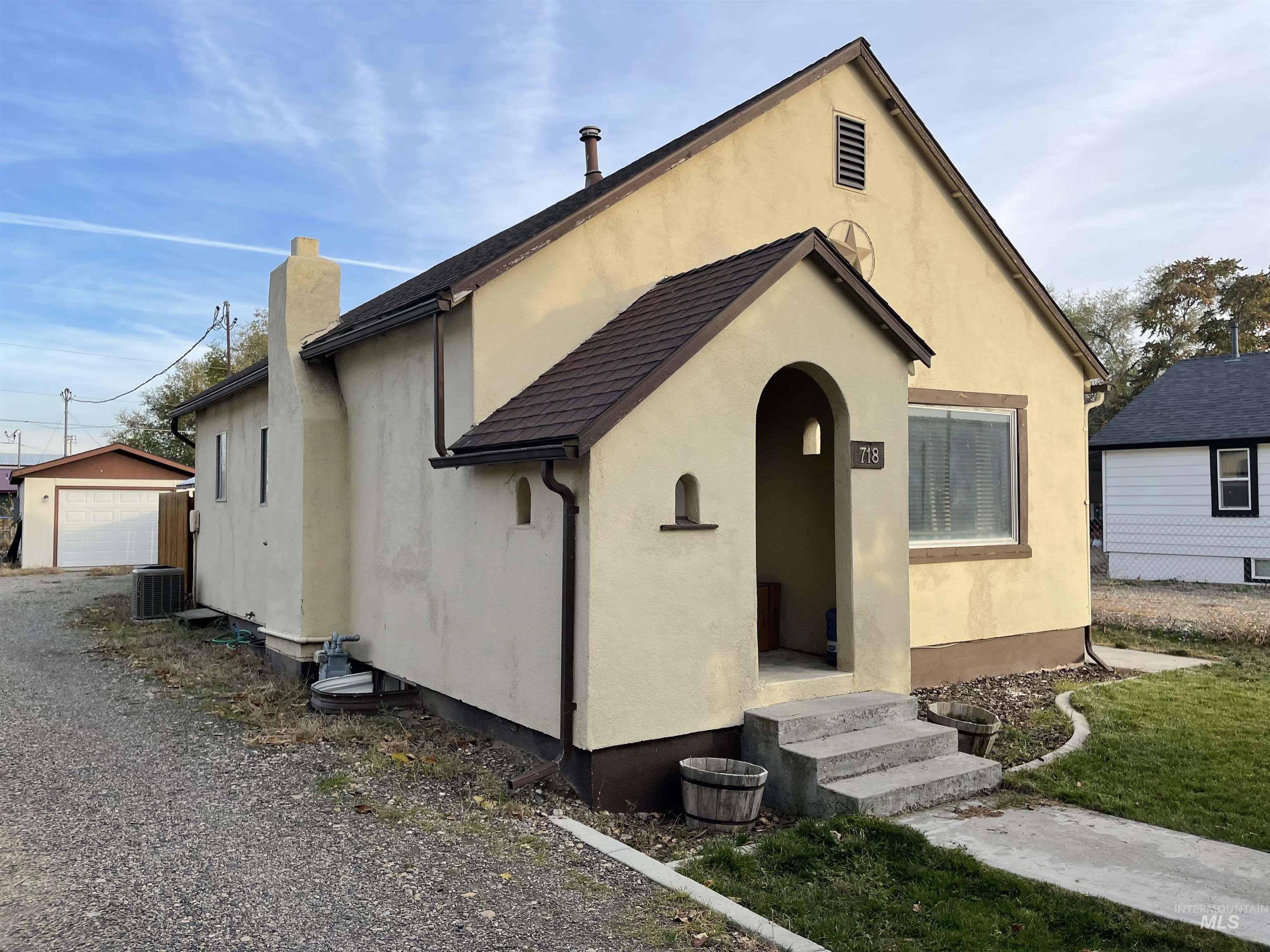 View of front of home featuring stucco siding, an outbuilding, a chimney, a detached garage, and a front yard