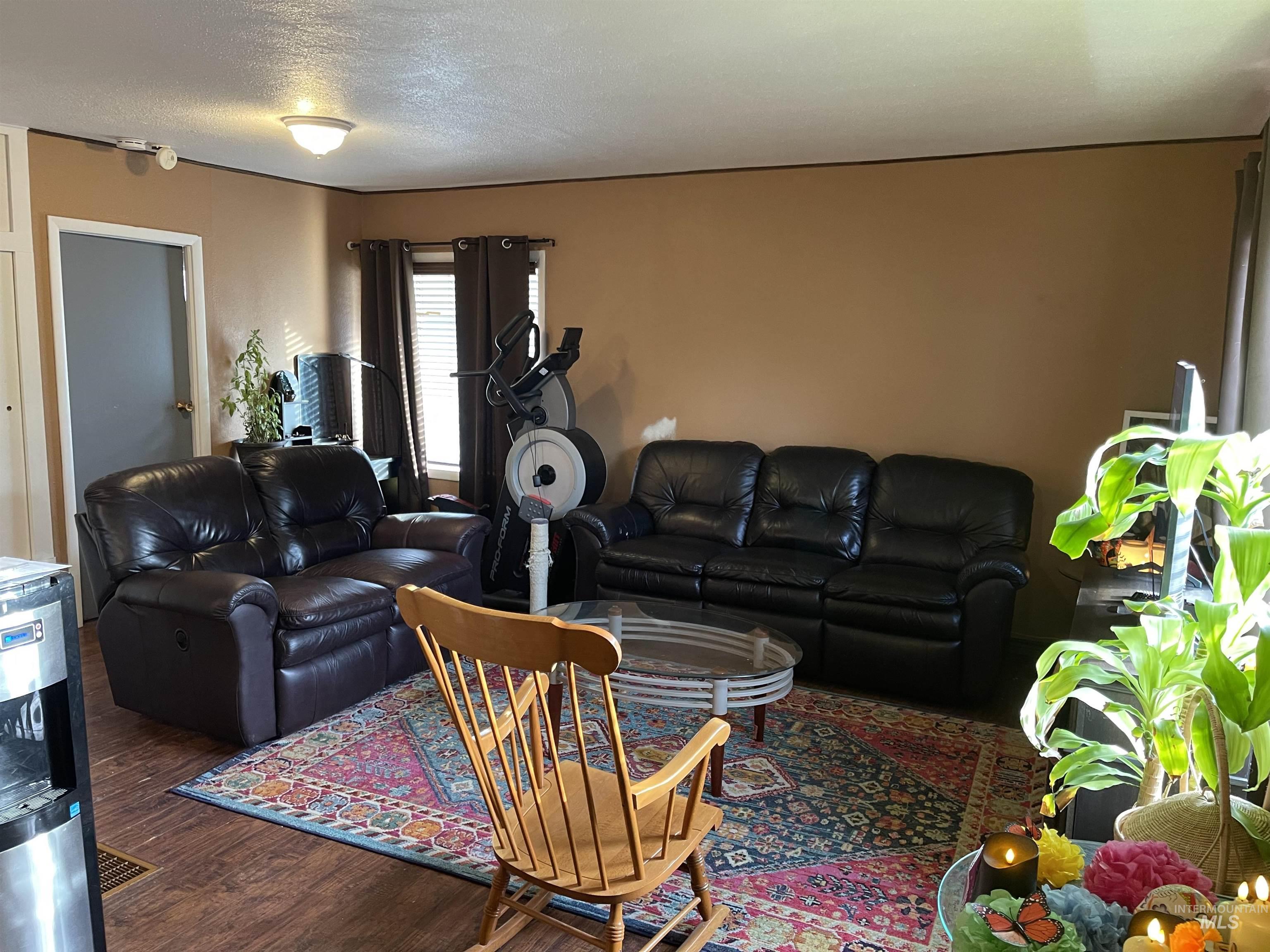 Living area with dark wood-style flooring and a textured ceiling