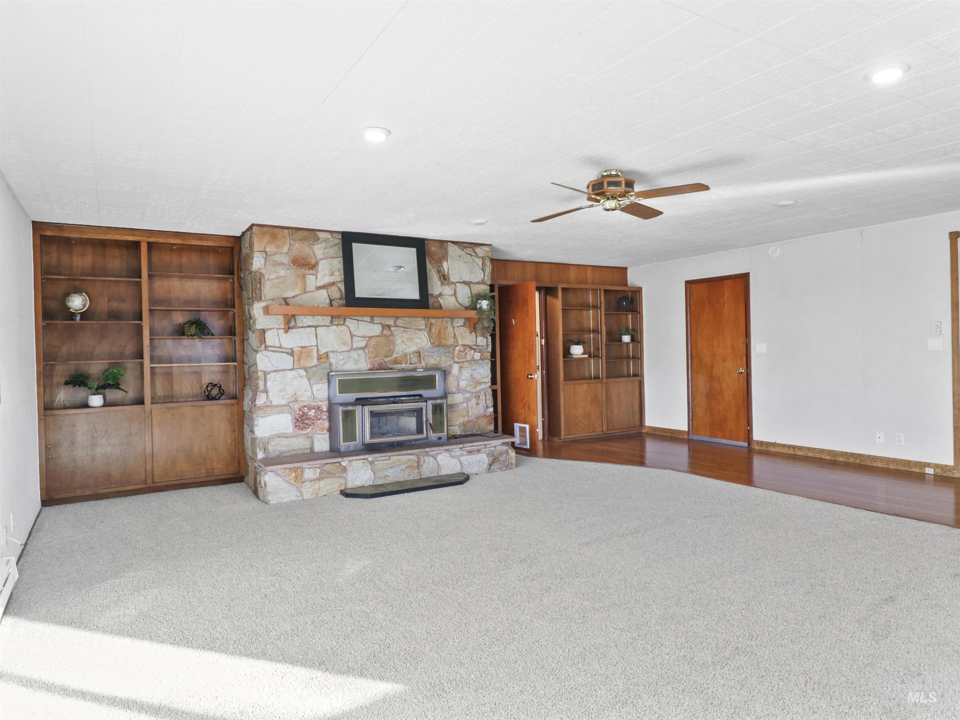 Unfurnished living room with a fireplace, a ceiling fan, and carpet