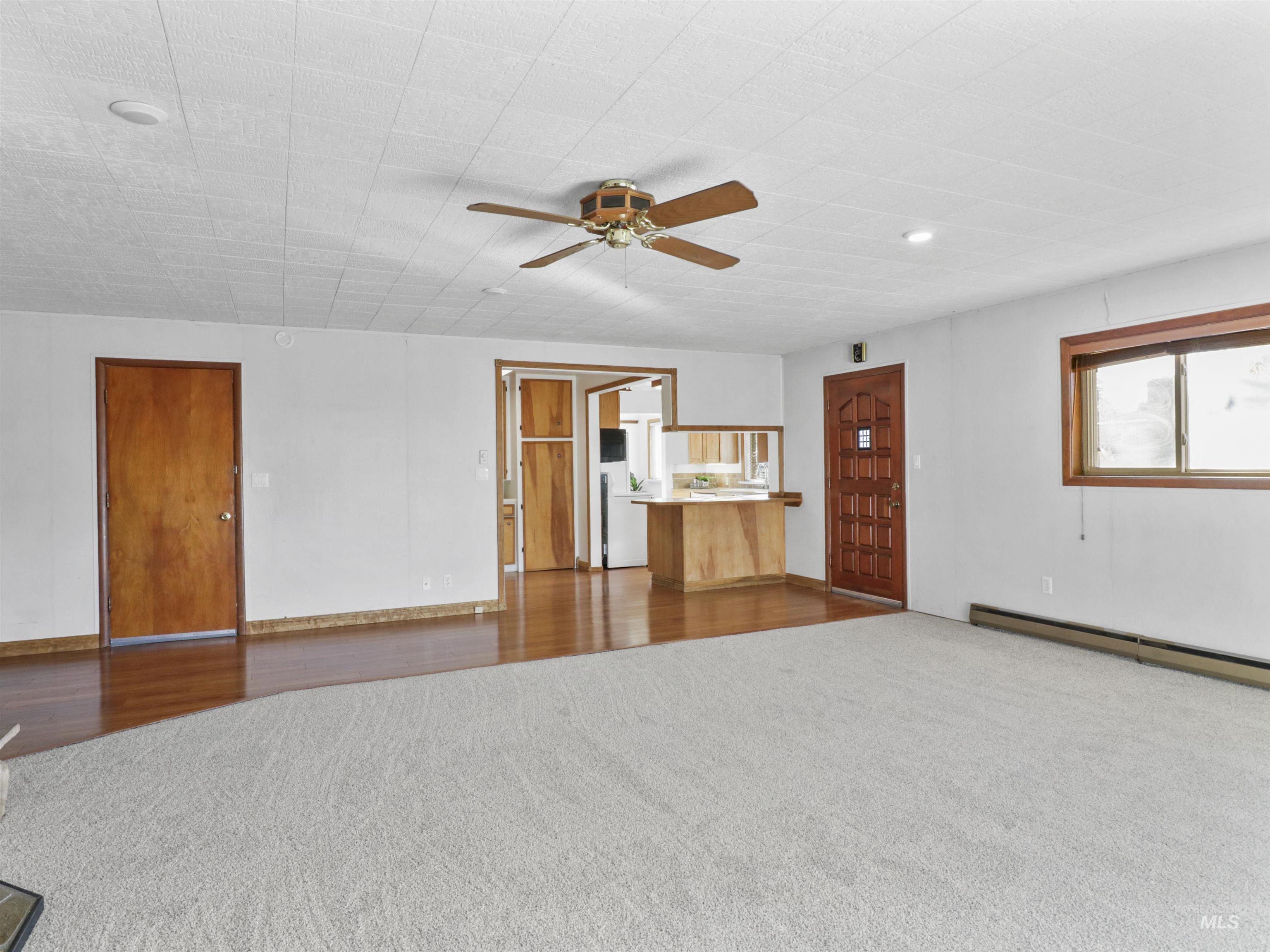 Unfurnished living room with dark carpet, a ceiling fan, and dark wood-style flooring