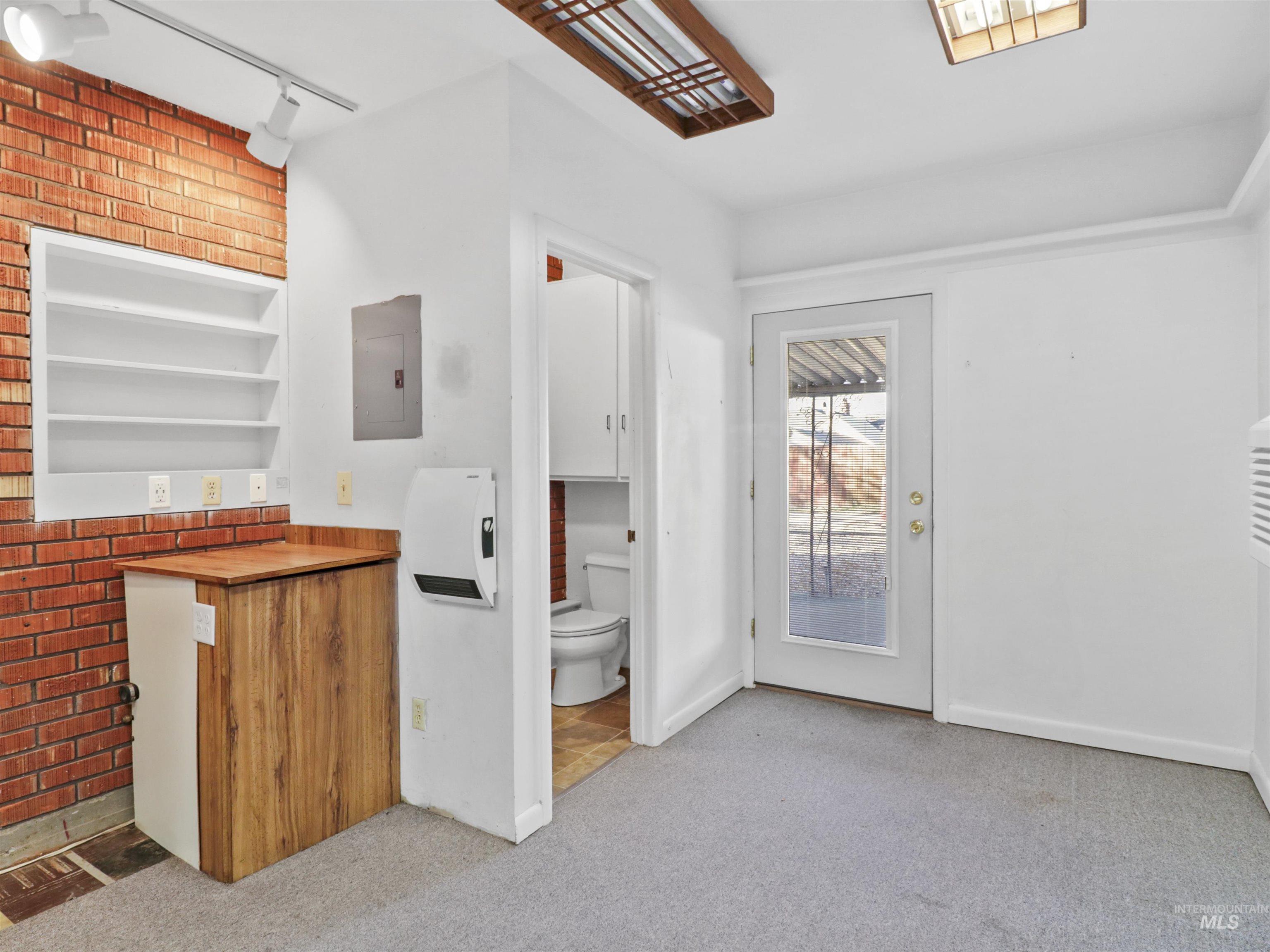 Bar featuring butcher block countertops, open shelves, light colored carpet, electric panel, and built in shelves
