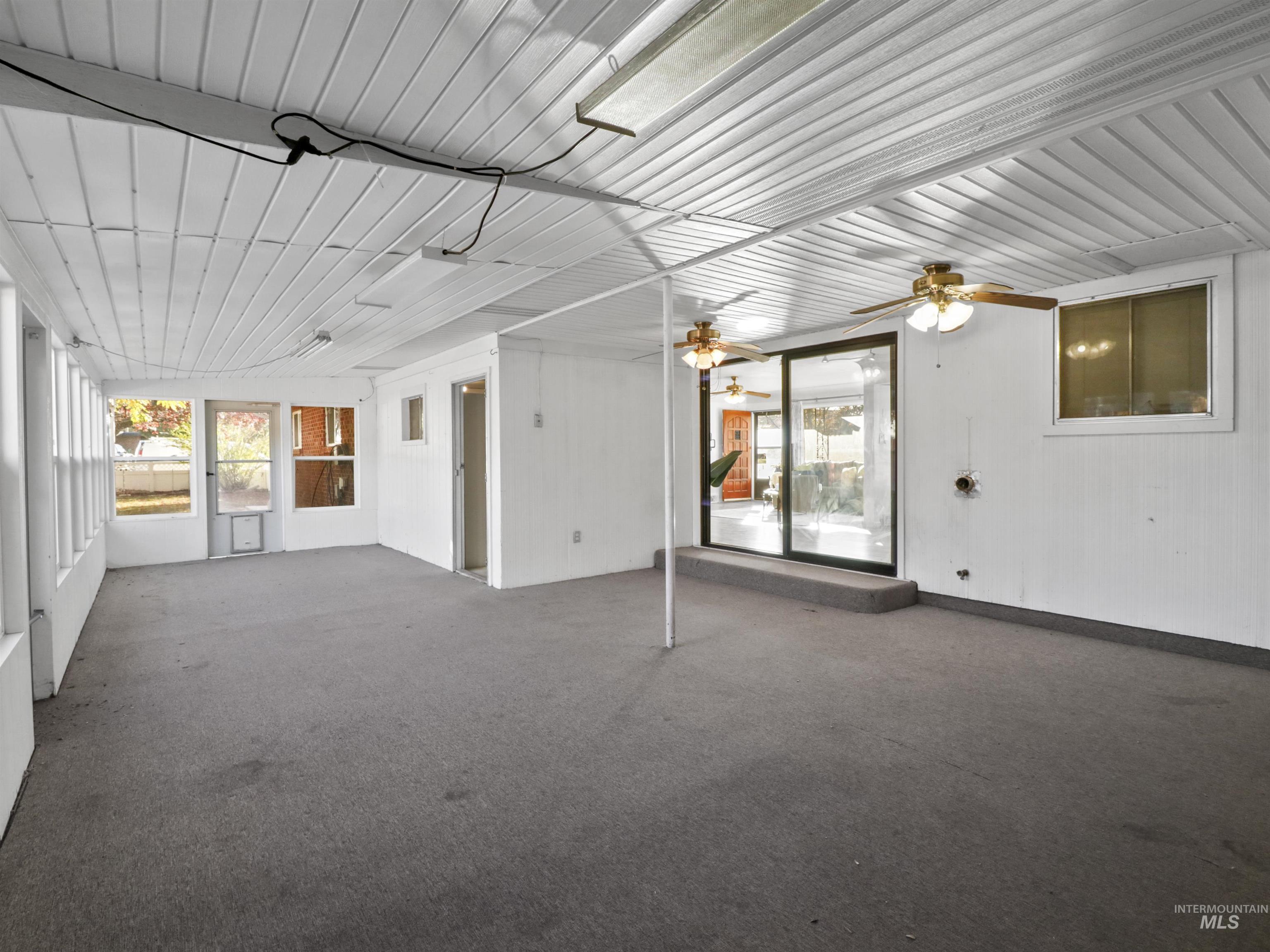 Unfurnished sunroom featuring carpet floors and a ceiling fan