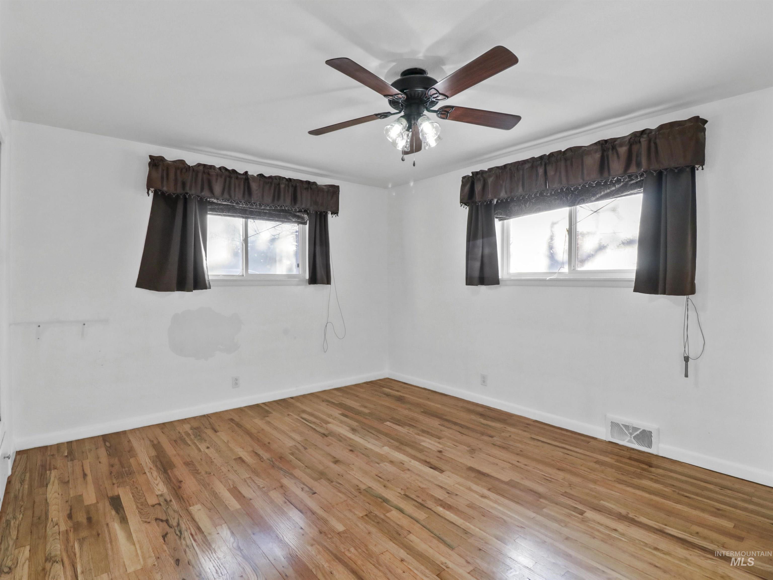 Unfurnished room featuring healthy amount of natural light, hardwood / wood-style flooring, and ceiling fan