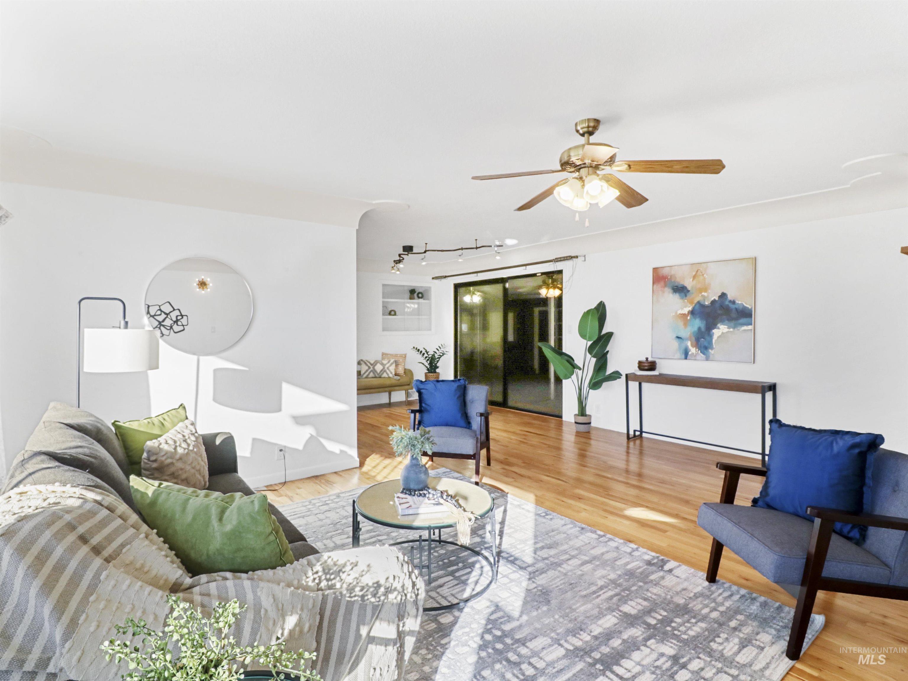 Living area with light wood-style flooring, ceiling fan, and rail lighting