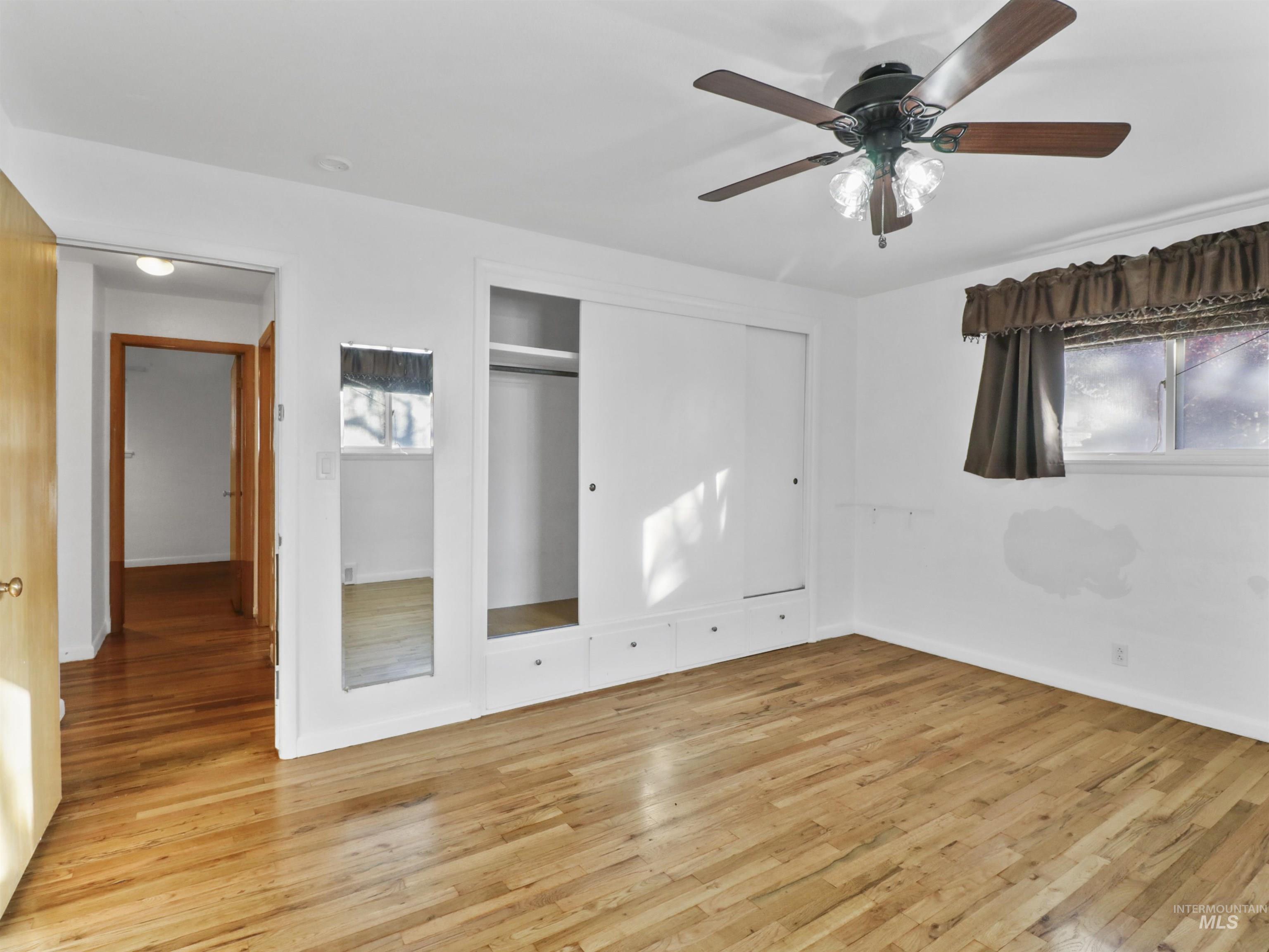 Unfurnished bedroom featuring light wood finished floors, a closet, and a ceiling fan