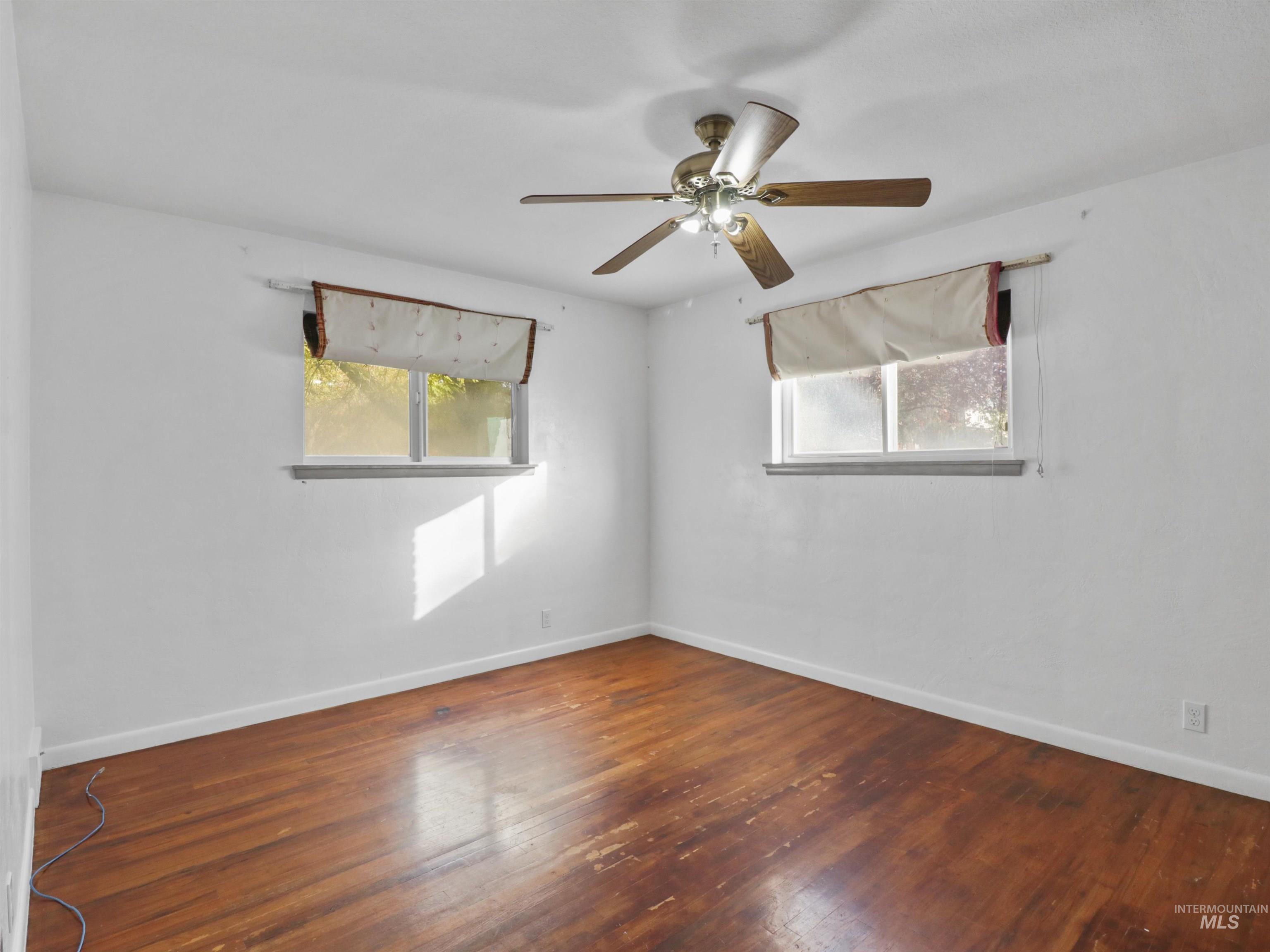 Spare room with dark wood finished floors and a ceiling fan