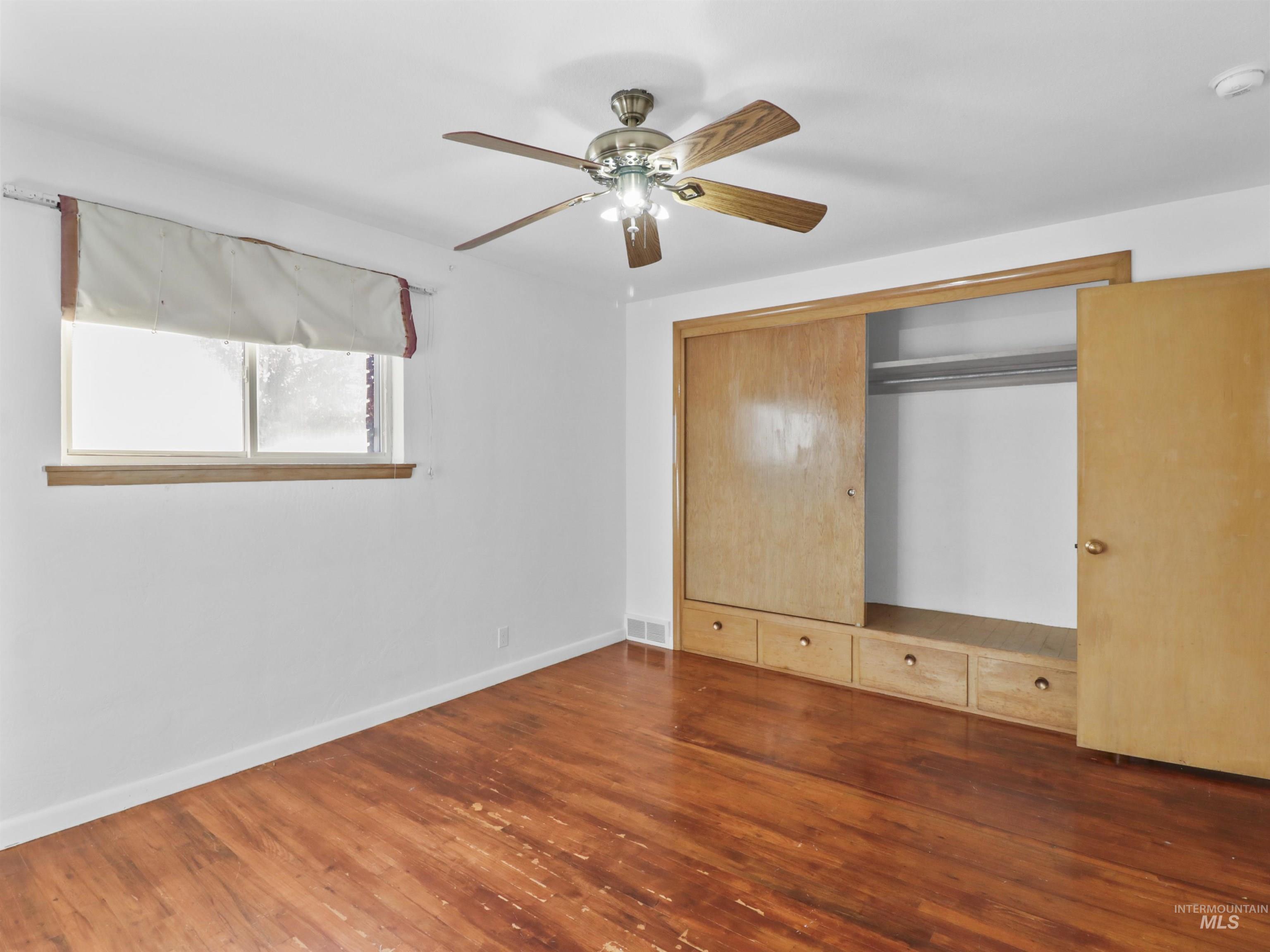 Unfurnished bedroom with dark wood finished floors, ceiling fan, and a closet