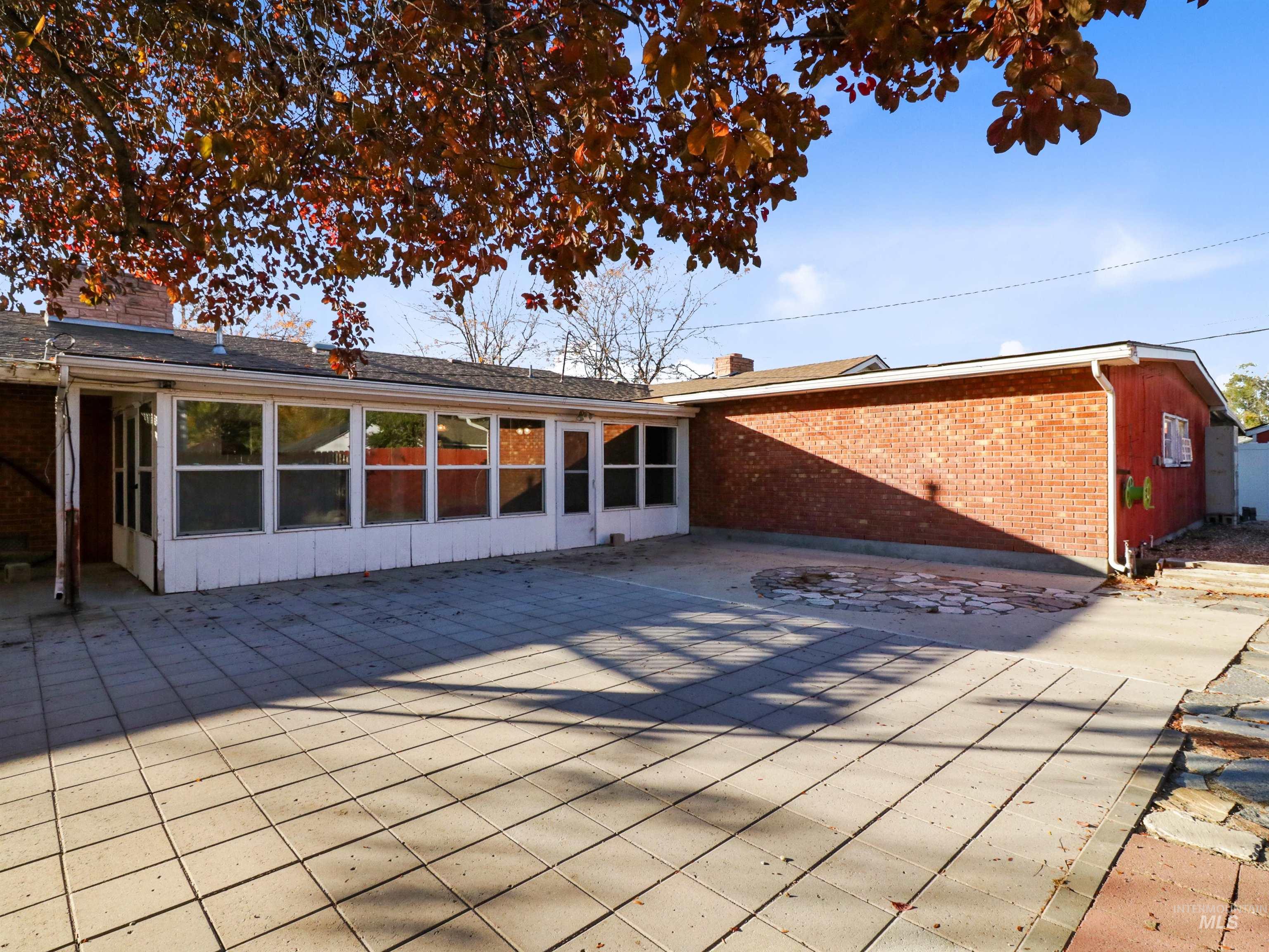 Back of house with a sunroom, a patio, brick siding, and a chimney