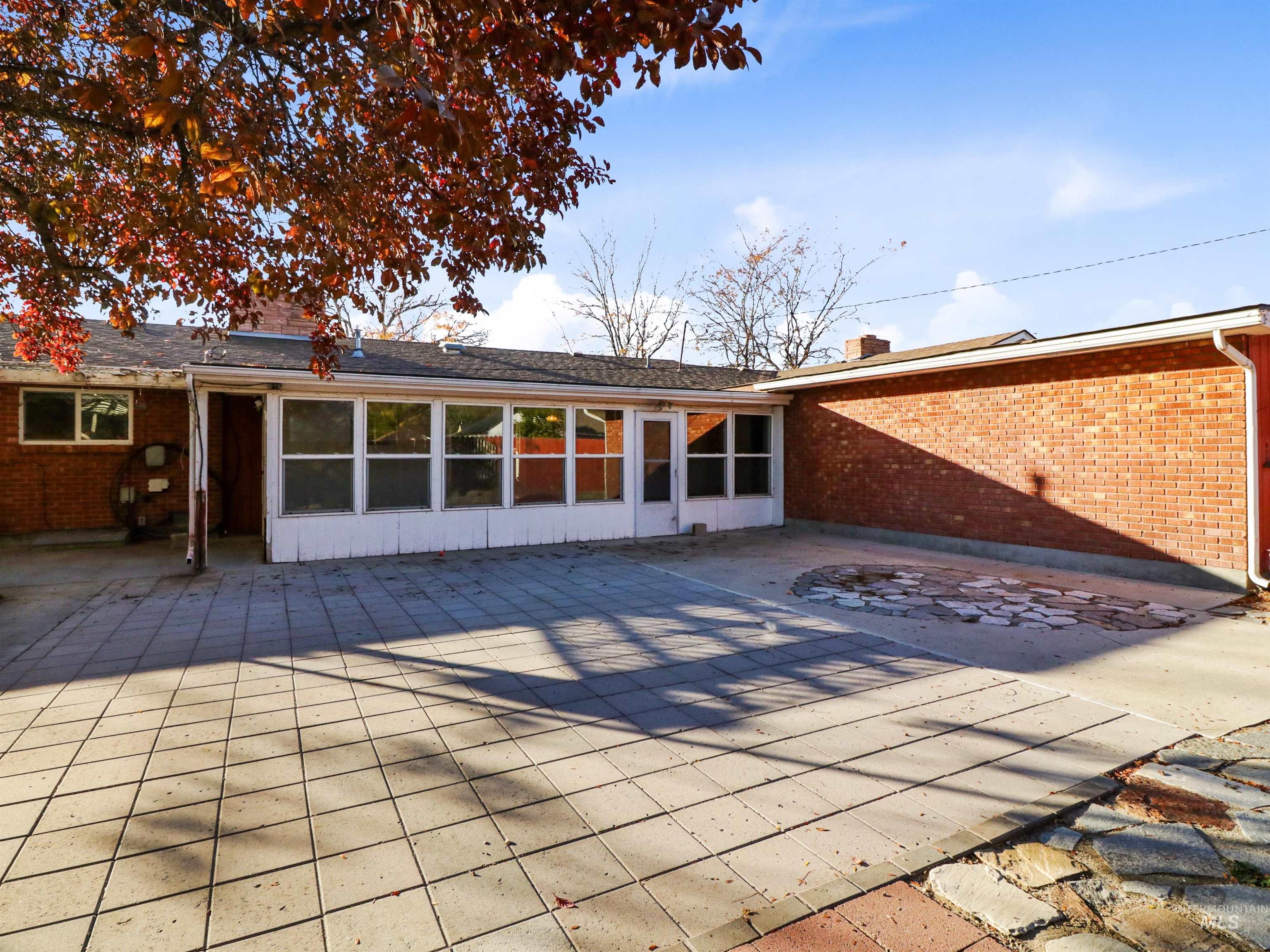 Back of house with a patio area, brick siding, and a chimney