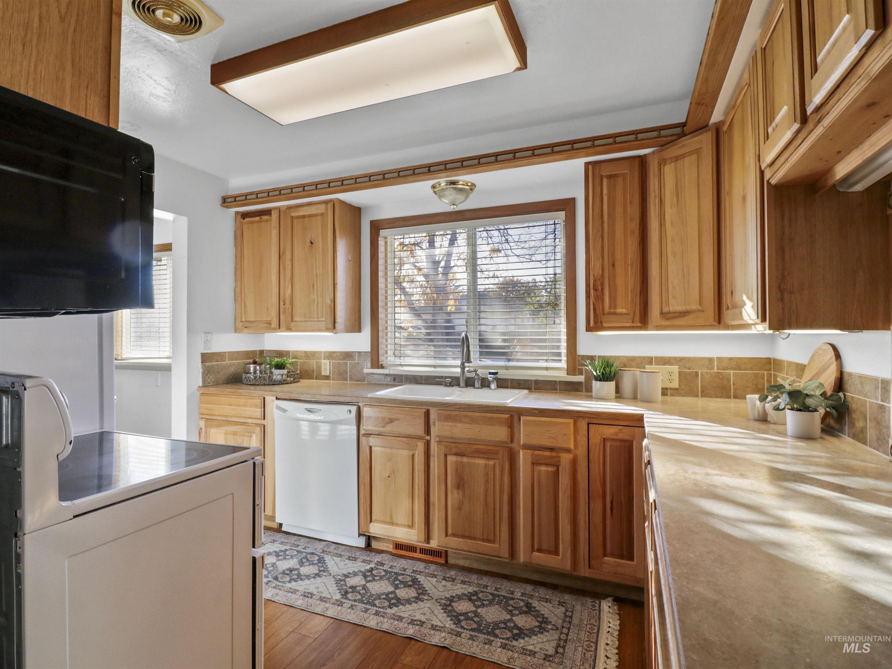 Kitchen featuring range, light countertops, dishwasher, and brown cabinetry