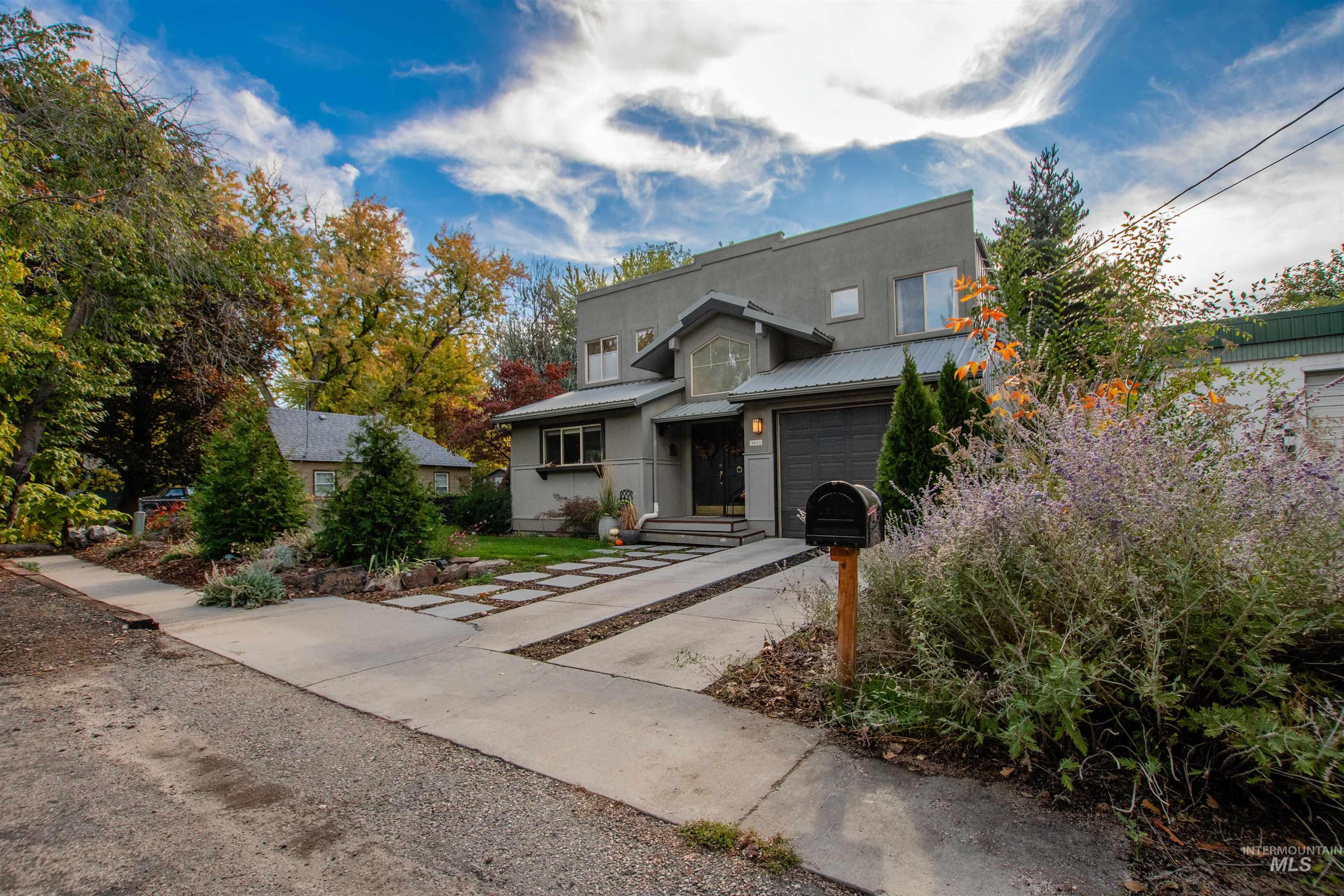 View of front of property with a metal roof, concrete driveway, and stucco siding