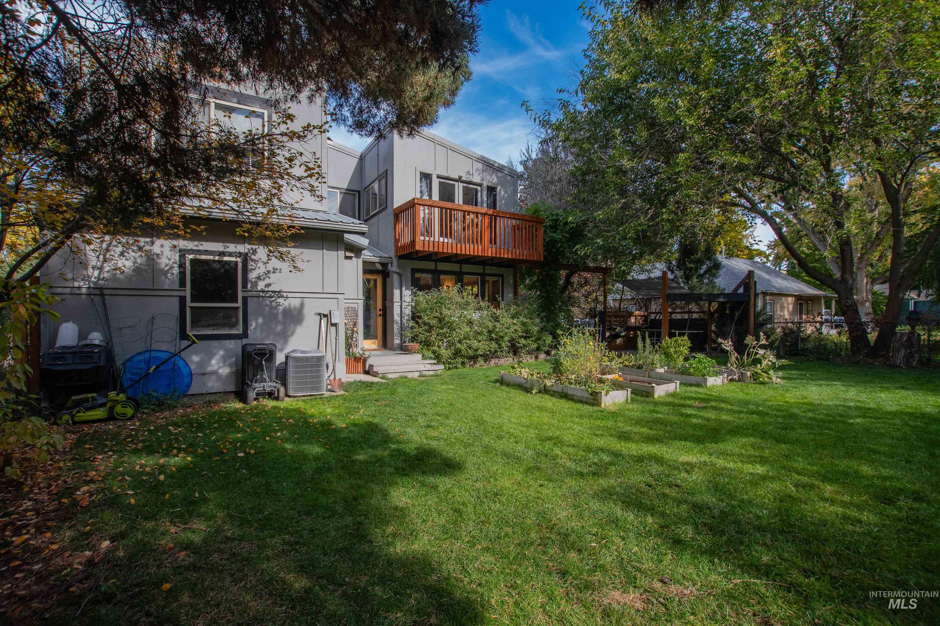 Rear view of property with a vegetable garden, a metal roof, and a wooden deck