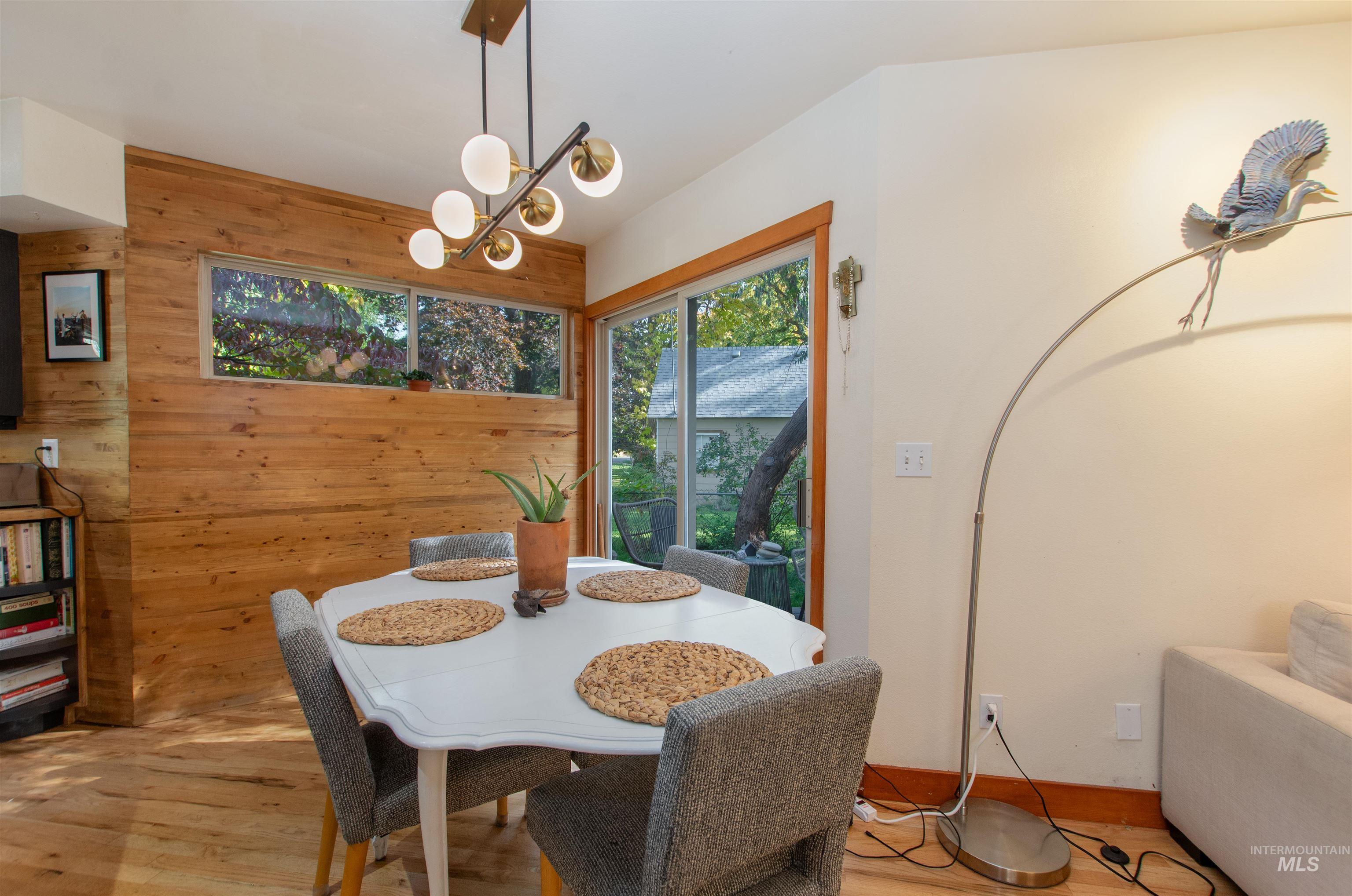 Dining room featuring wooden walls, wood finished floors, and a chandelier