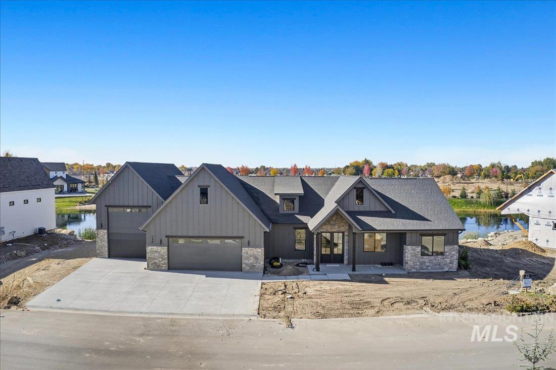 Modern farmhouse style home featuring stone siding, a porch, concrete driveway, and board and batten siding