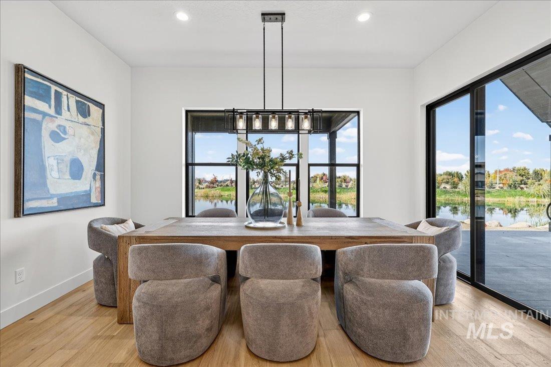 Dining room with a water view, light wood-style flooring, and recessed lighting