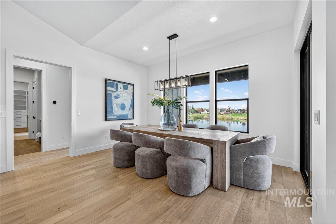 Dining space with light wood-style flooring, a chandelier, recessed lighting, and a water view